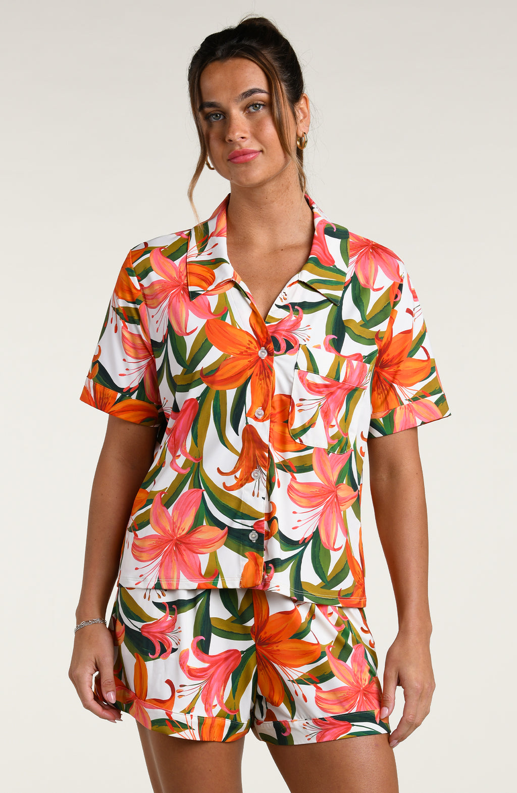 Woman wearing a colorful tropical long sleeve and short pajama set against a white background.