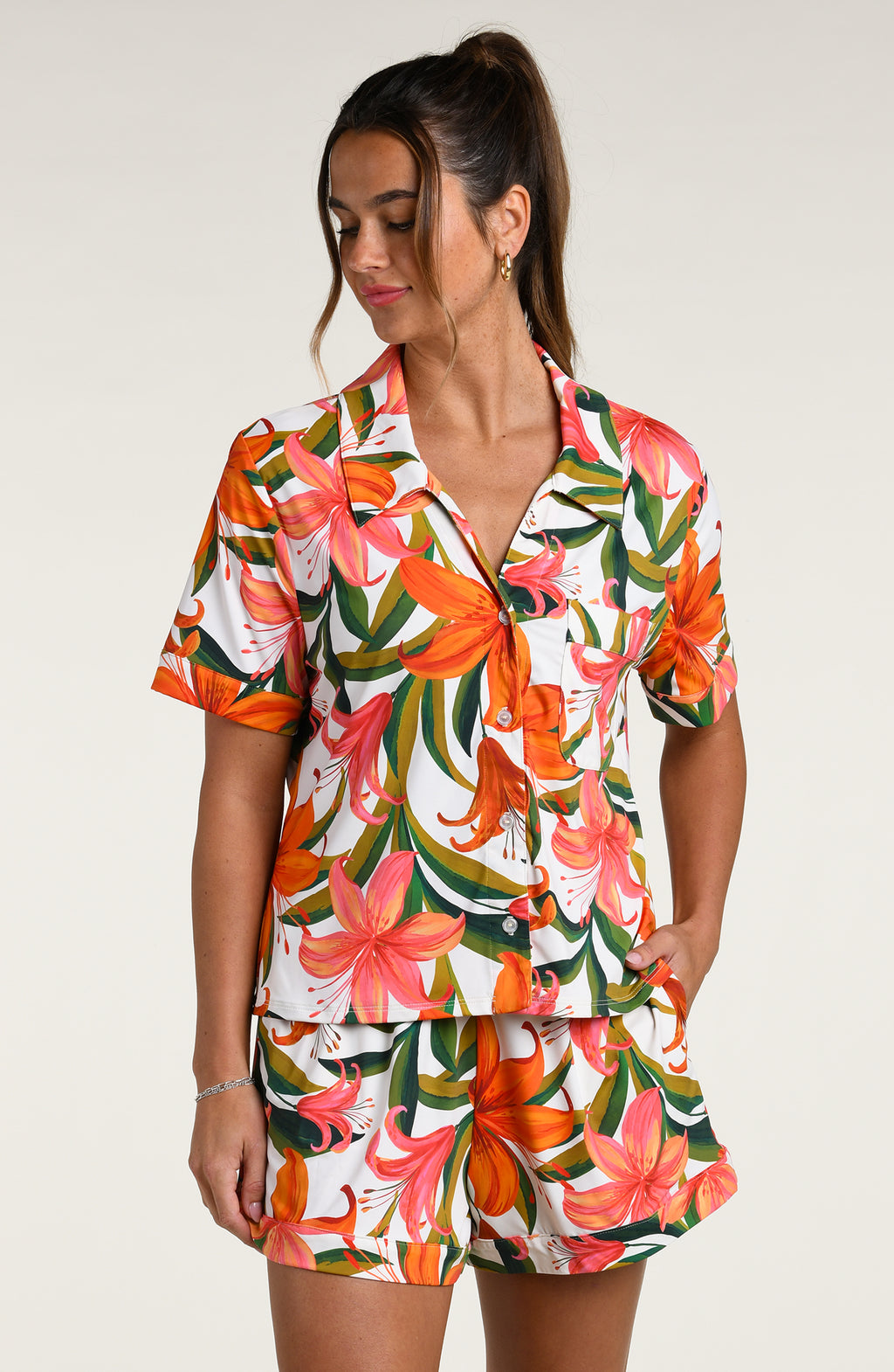 Woman wearing a colorful tropical long sleeve and short pajama set against a white background.
