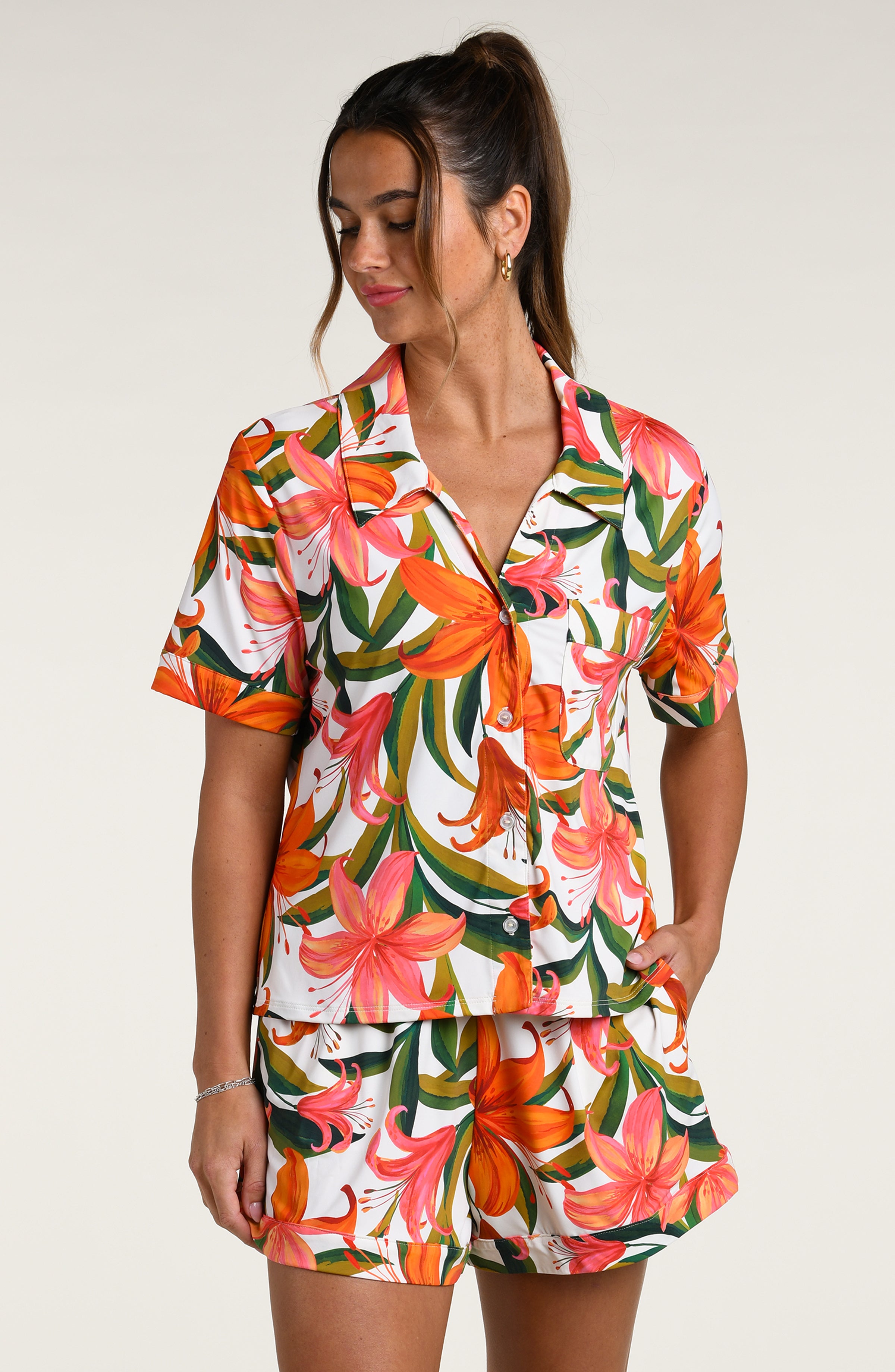 Woman wearing a colorful tropical long sleeve and short pajama set against a white background.