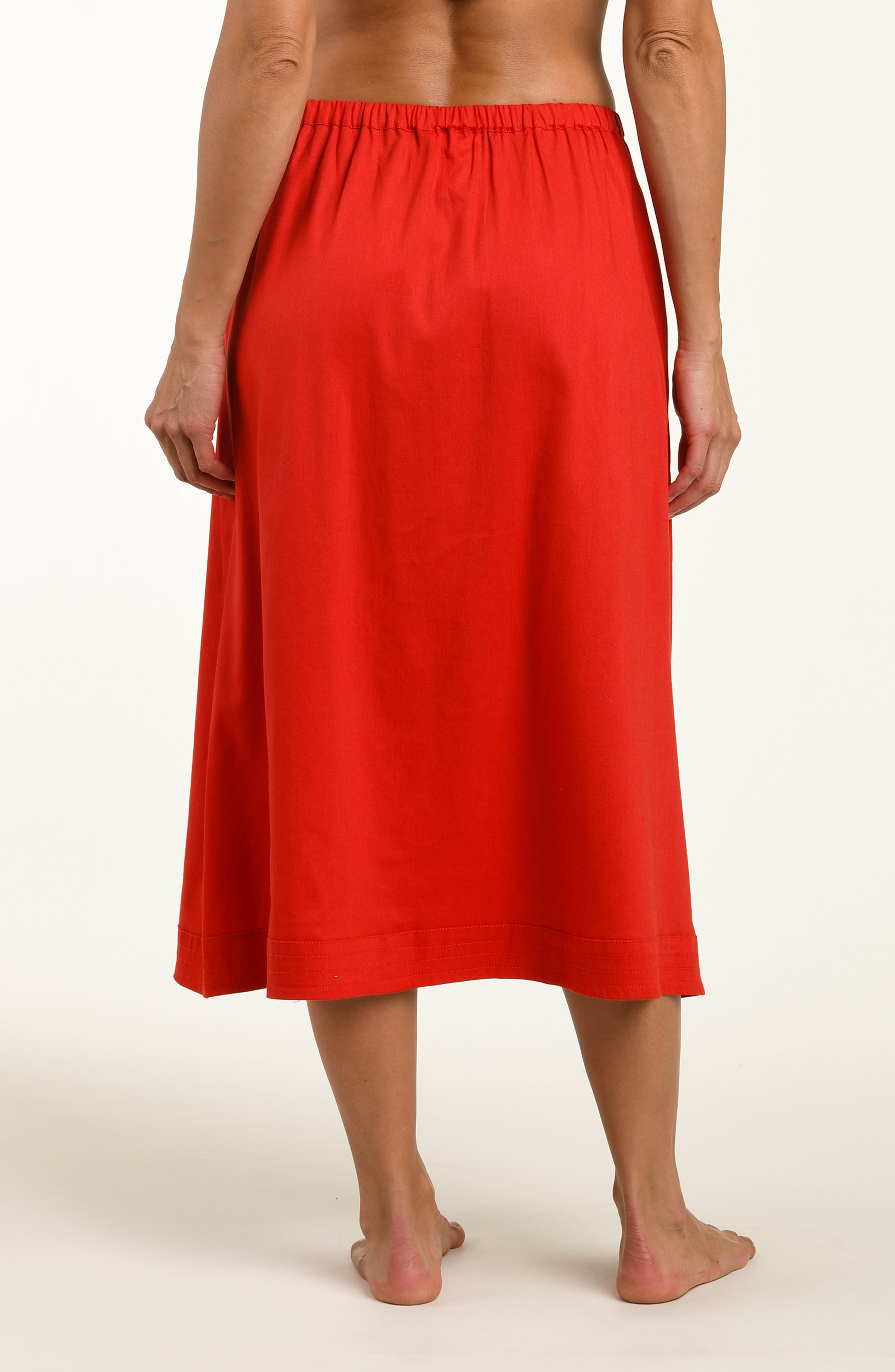 Woman wearing a red cover up skirt against a white background.