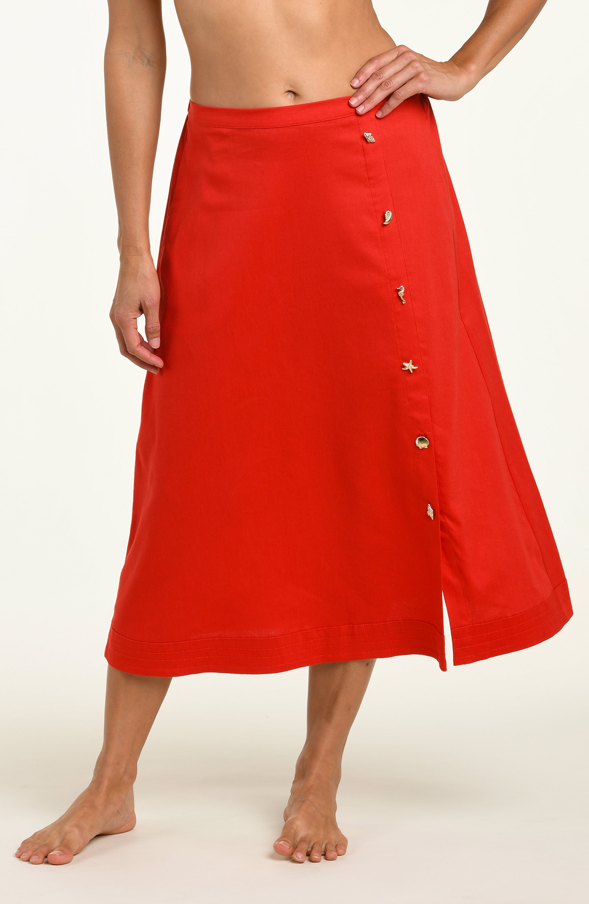 Woman wearing a red cover up skirt against a white background.