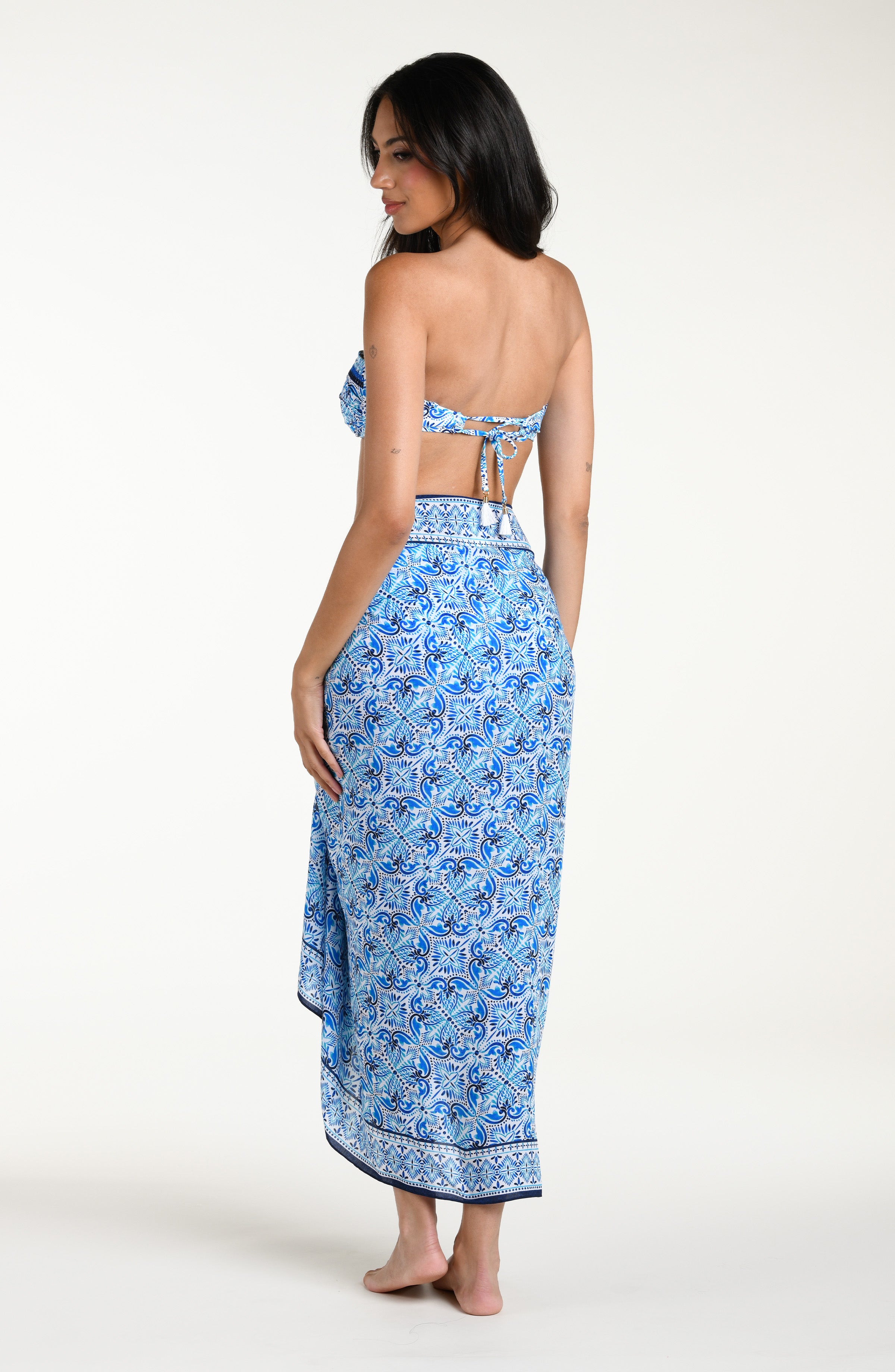 Woman wearing a blue floral patterned bikini top and matching pareo wrap against a white background