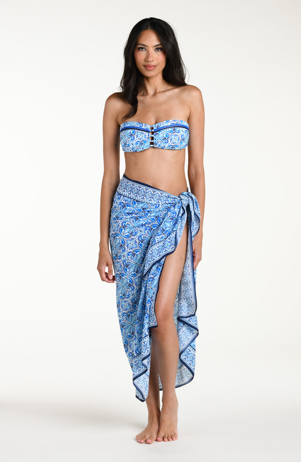 Woman wearing a blue floral patterned bikini top and matching pareo wrap against a white background