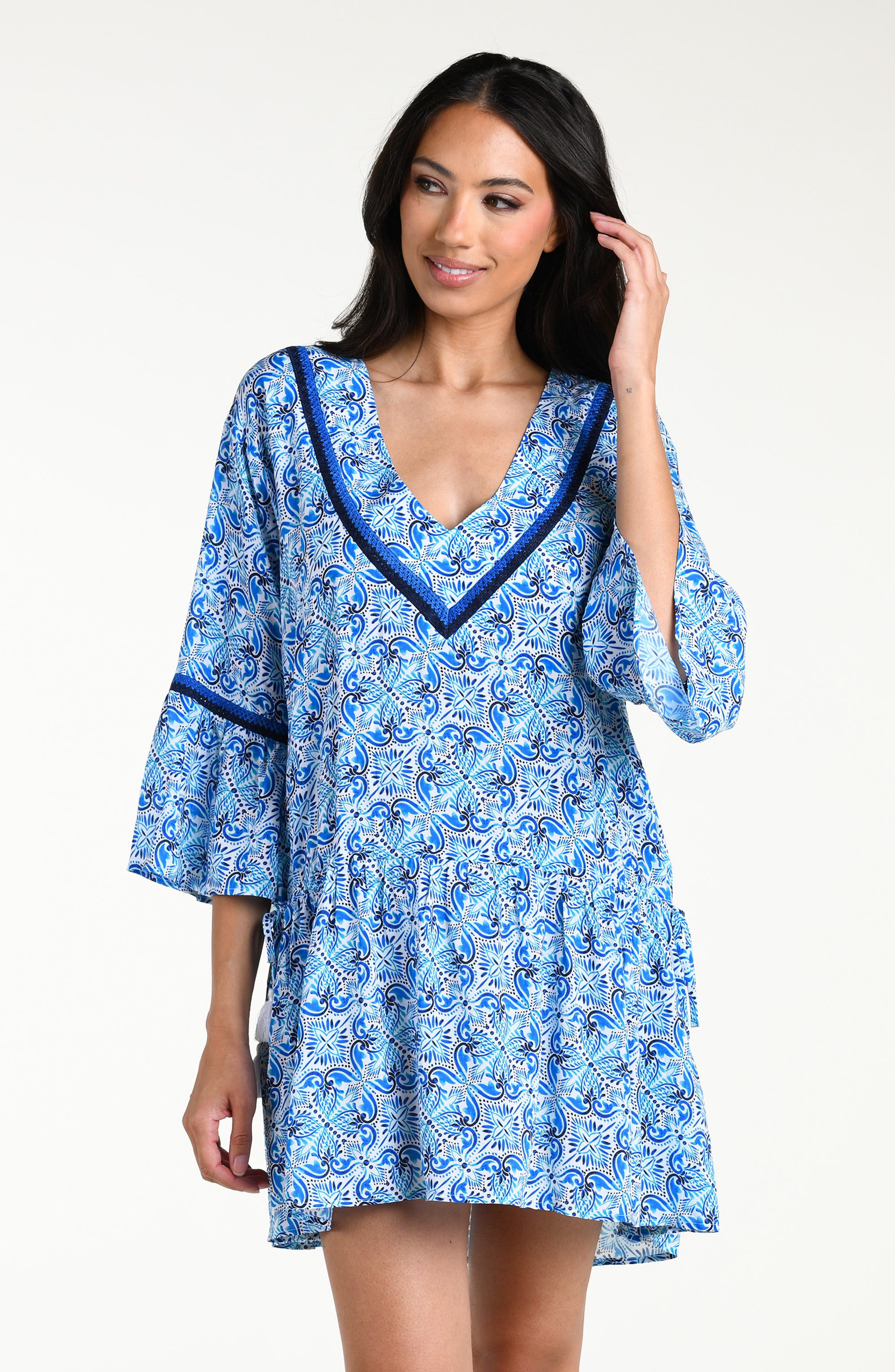 Woman wearing a blue floral patterned  V-neck tunic cover up against a white background
