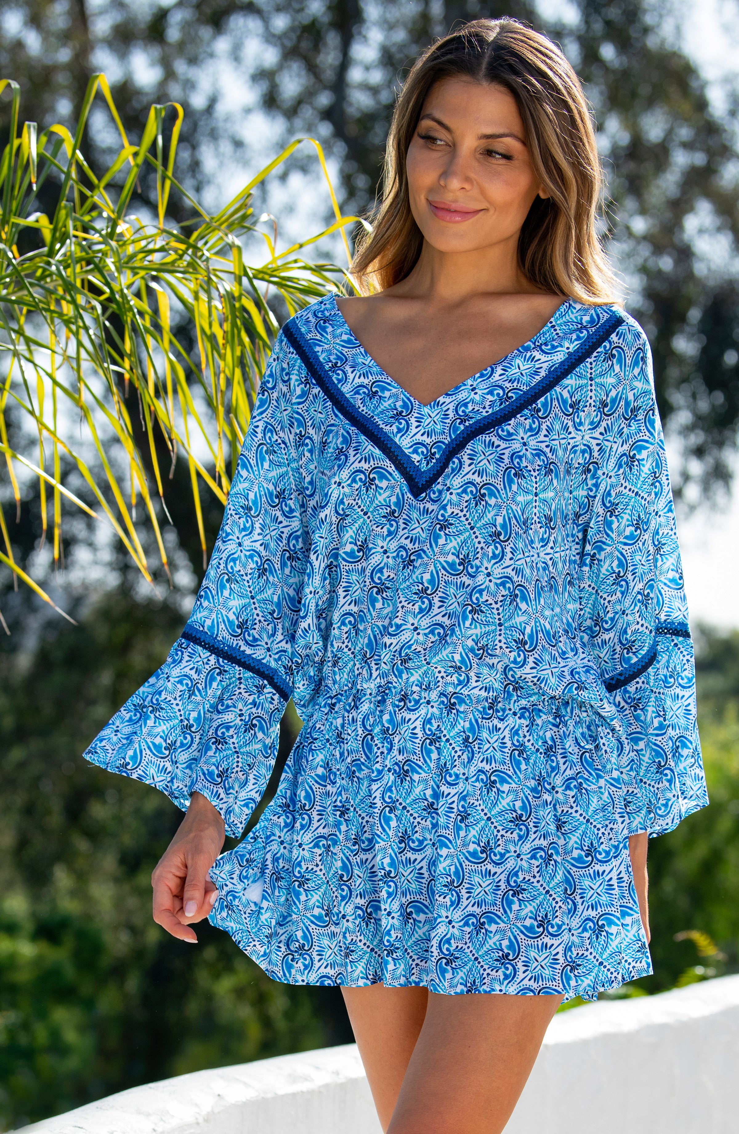 Woman wearing a blue floral patterned  V-neck tunic cover up standing outdoors.