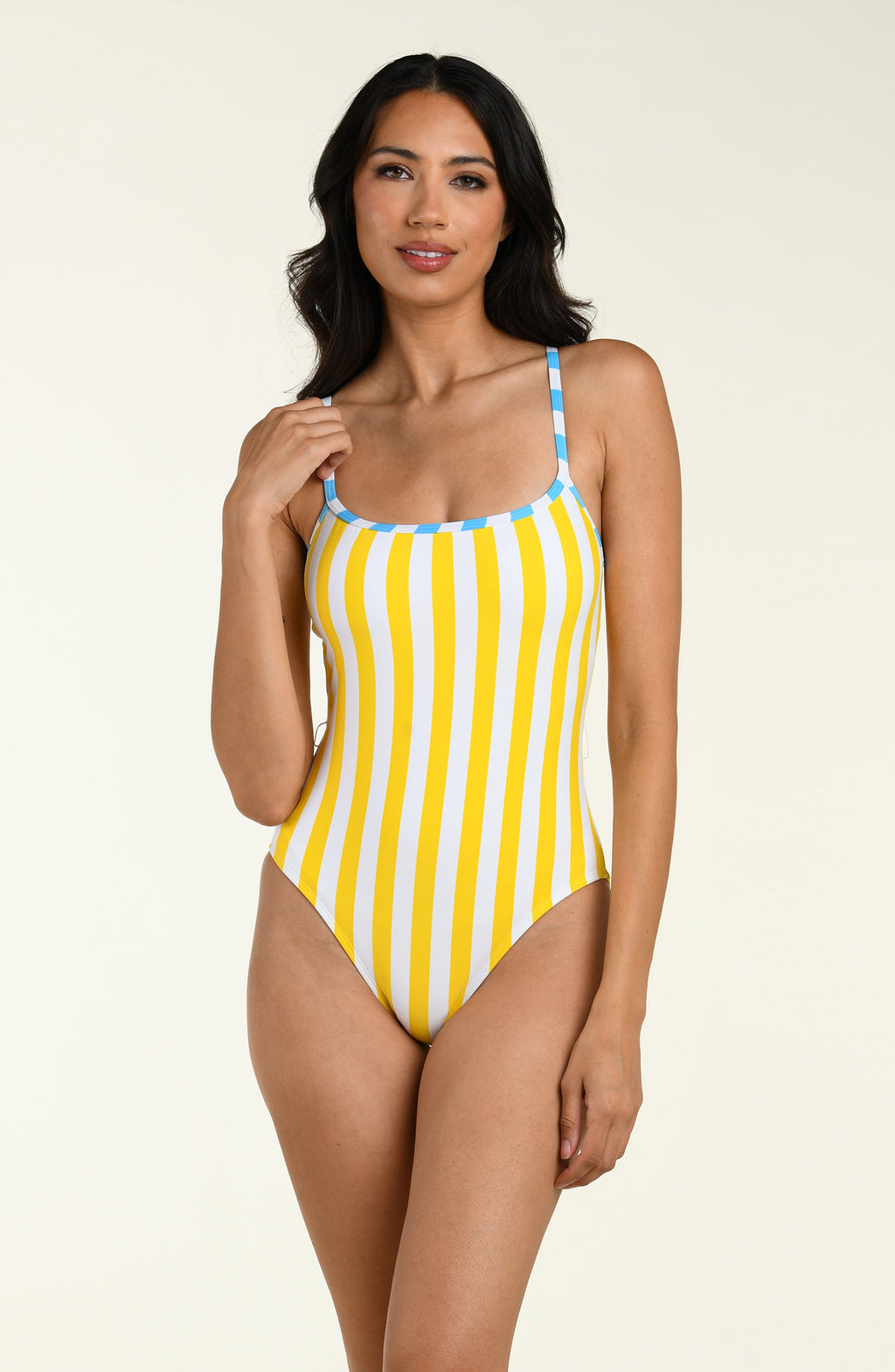 Woman wearing a yellow and blue striped one piece swimsuit on a beige background
