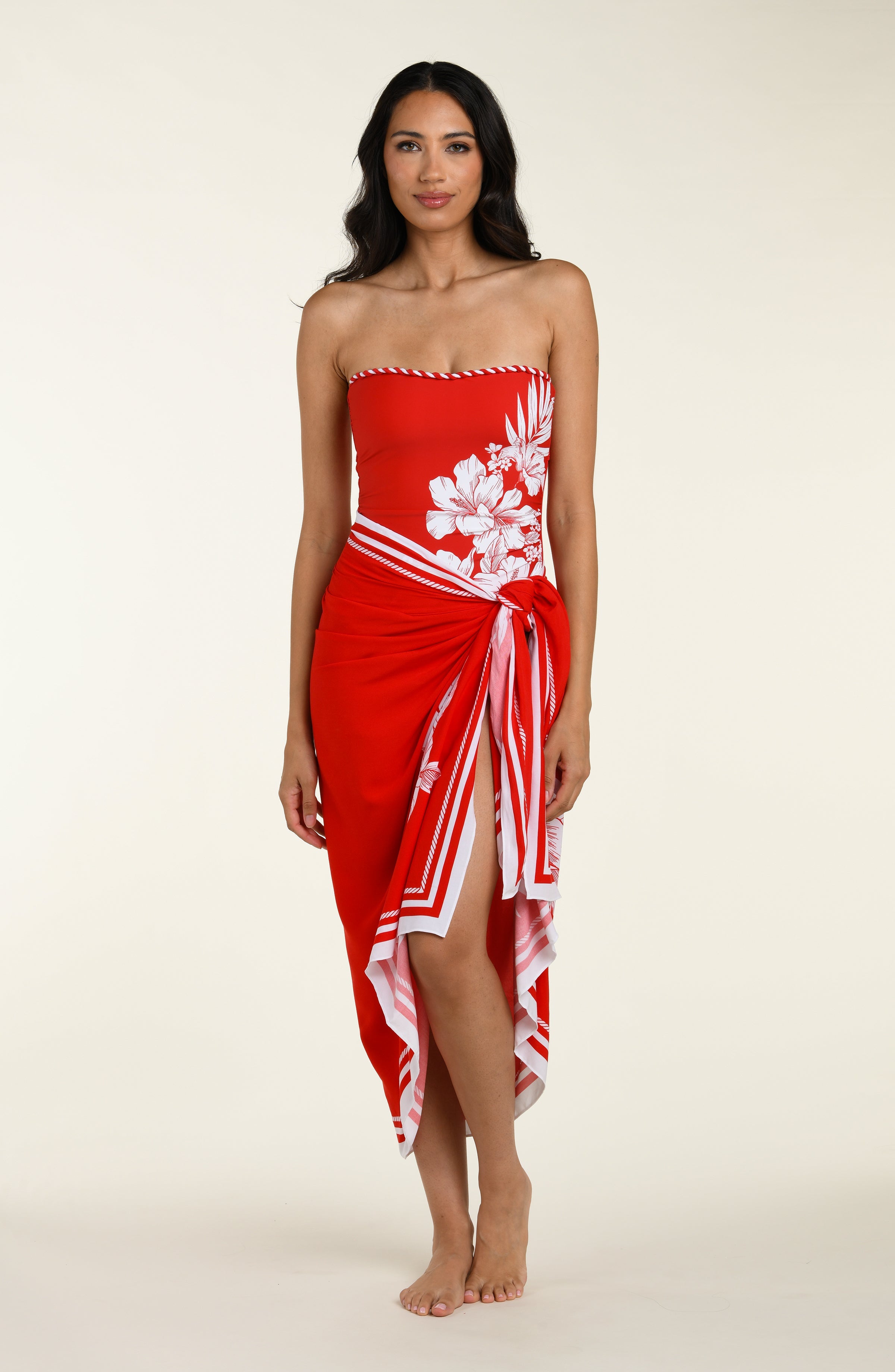 Woman wearing a red and white patterned sarong and a matching bikini top on a plain background