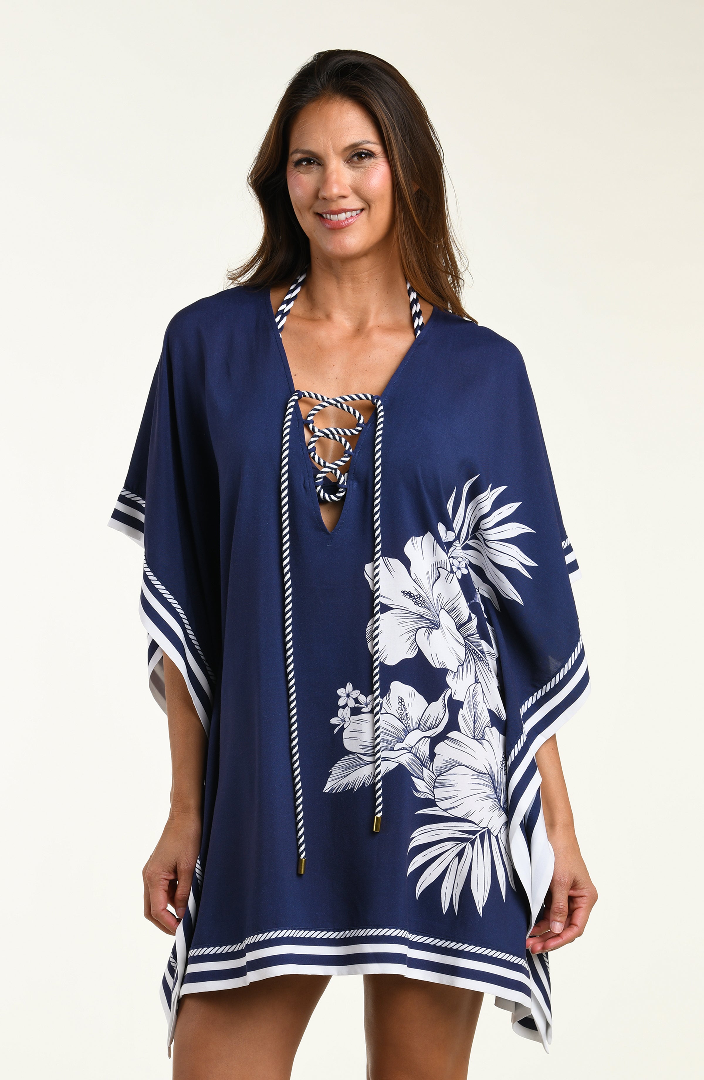 Woman wearing a navy blue tunic cover up with white floral patterns on a white background