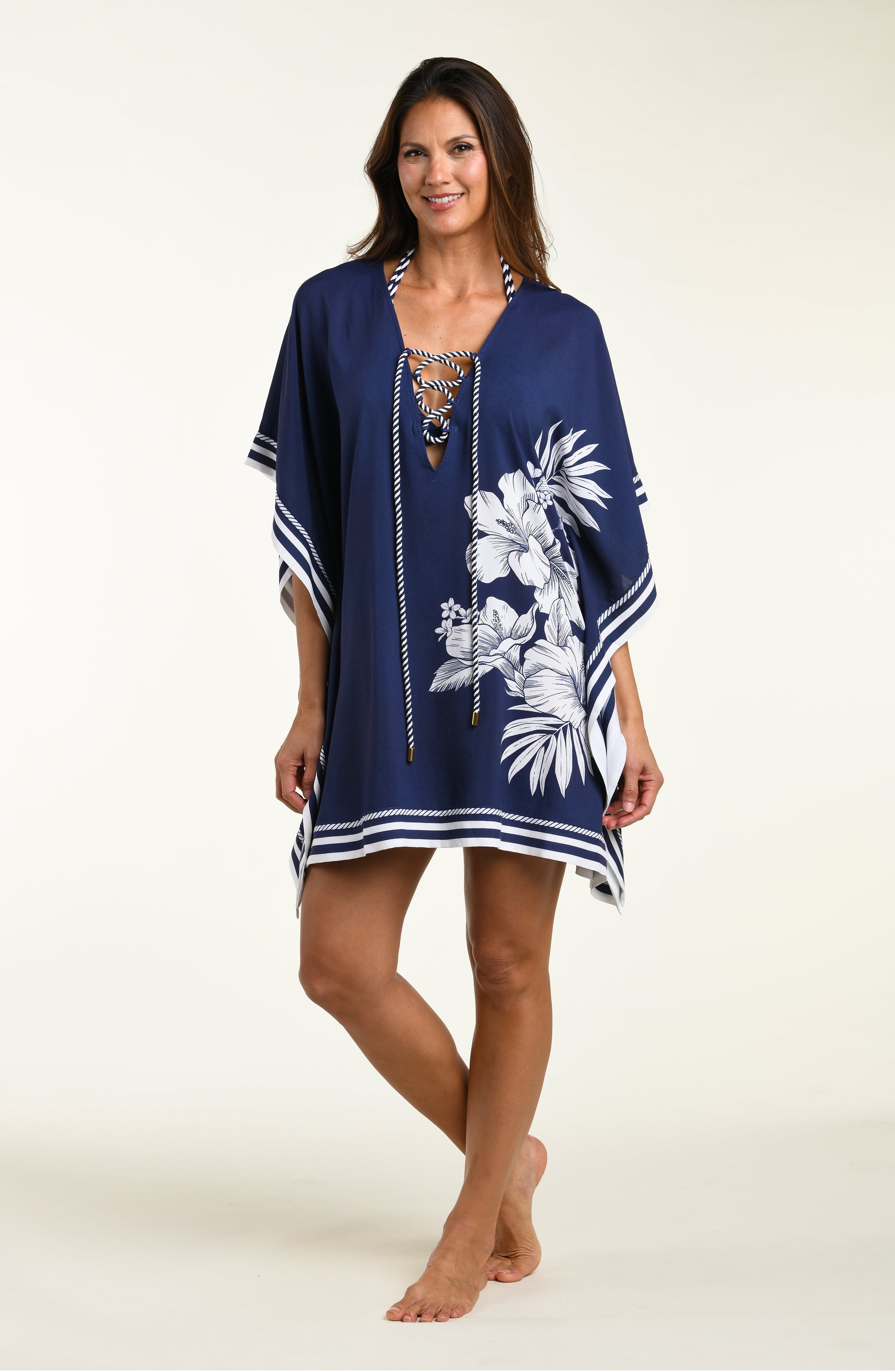 Woman wearing a navy blue tunic cover up with white floral patterns on a white background