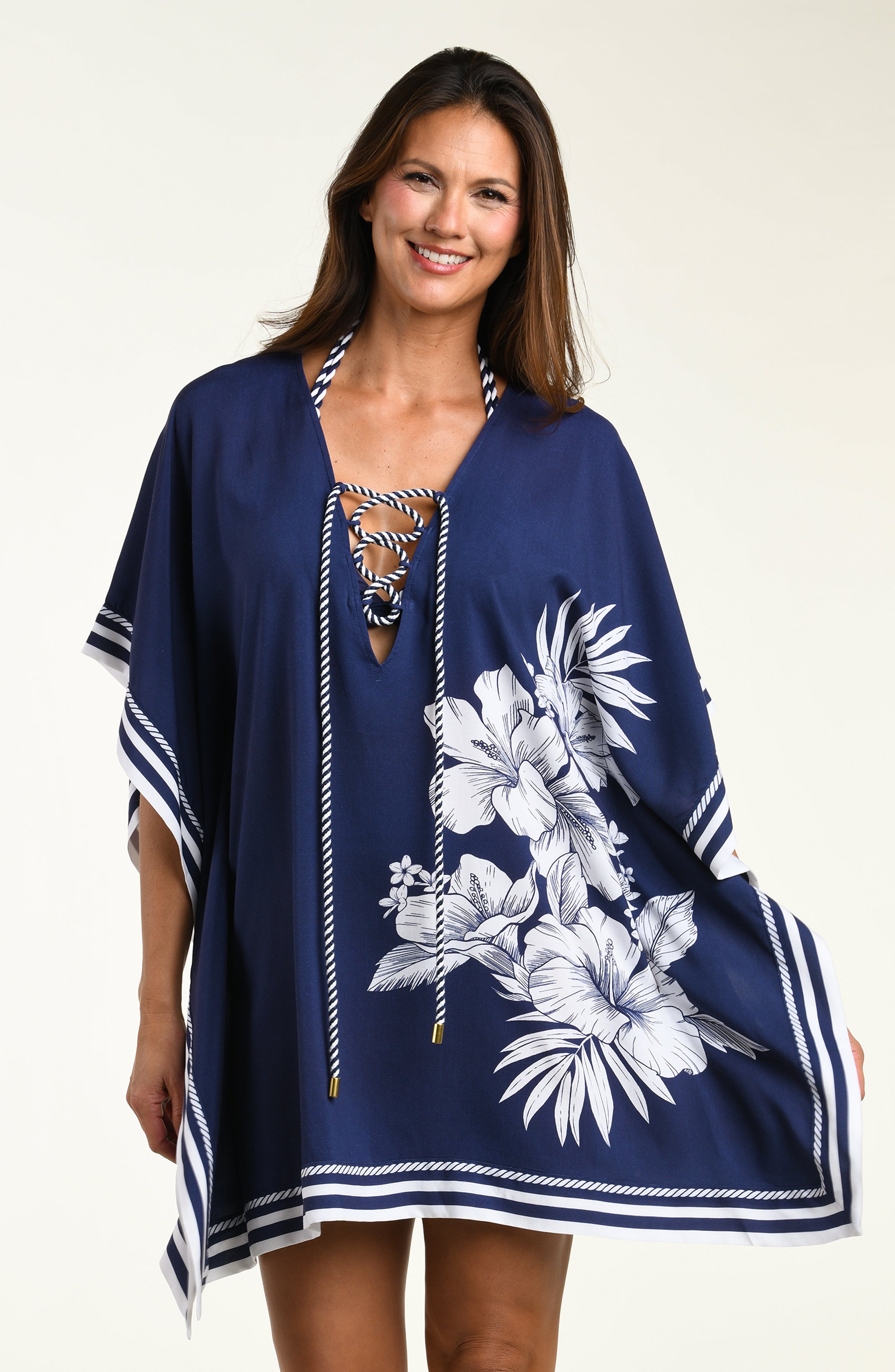 Woman wearing a navy blue tunic cover up with white floral patterns on a white background