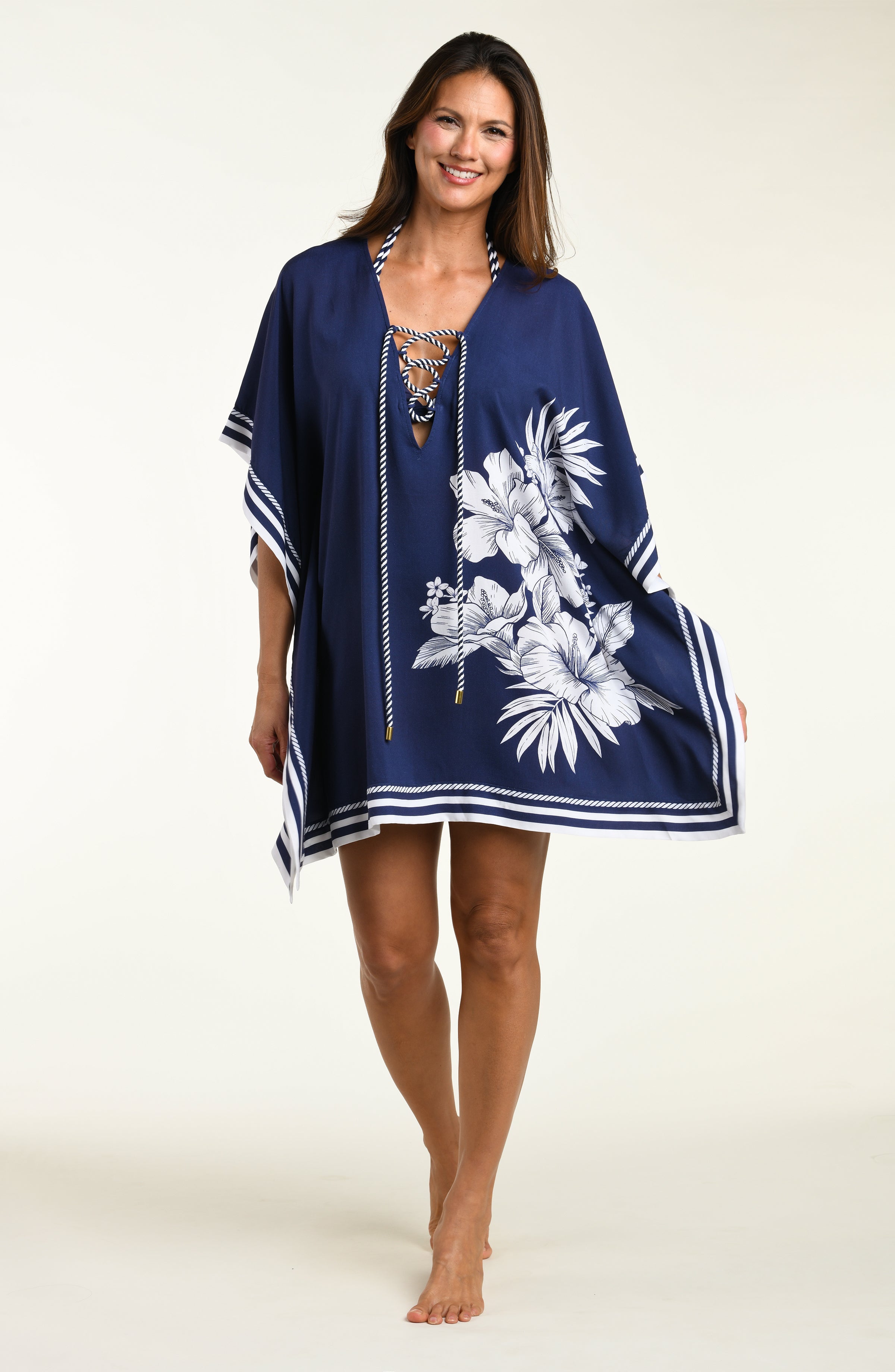 Woman wearing a navy blue tunic cover up with white floral patterns on a white background