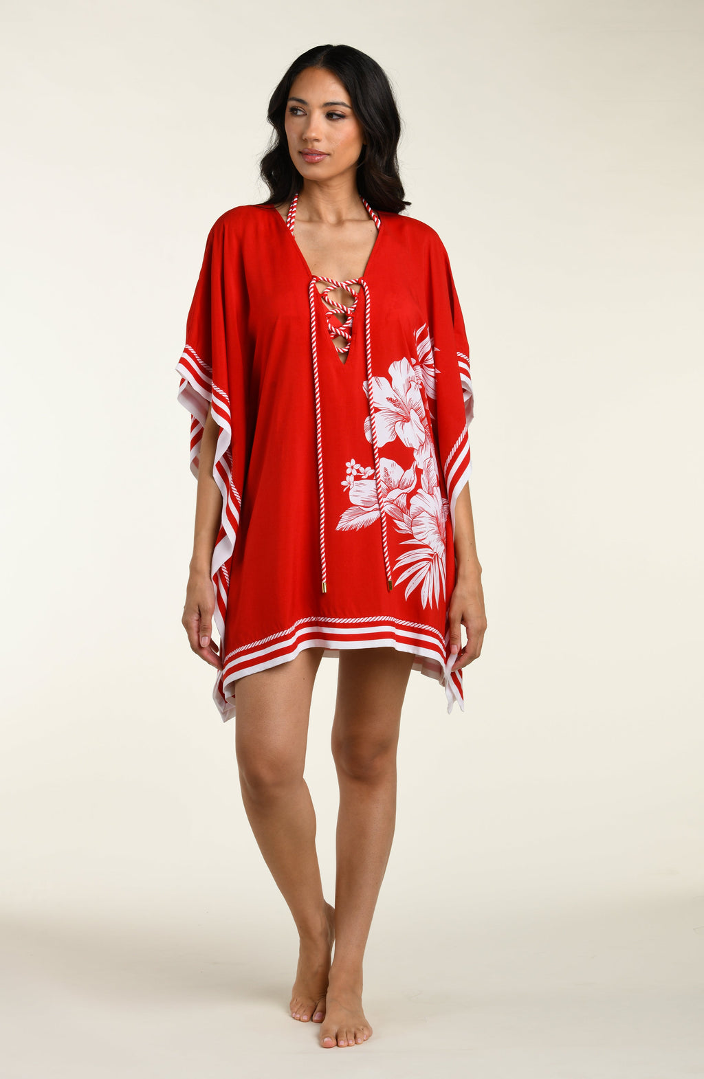 Woman wearing a red floral tunic cover up with white accents on a beige background