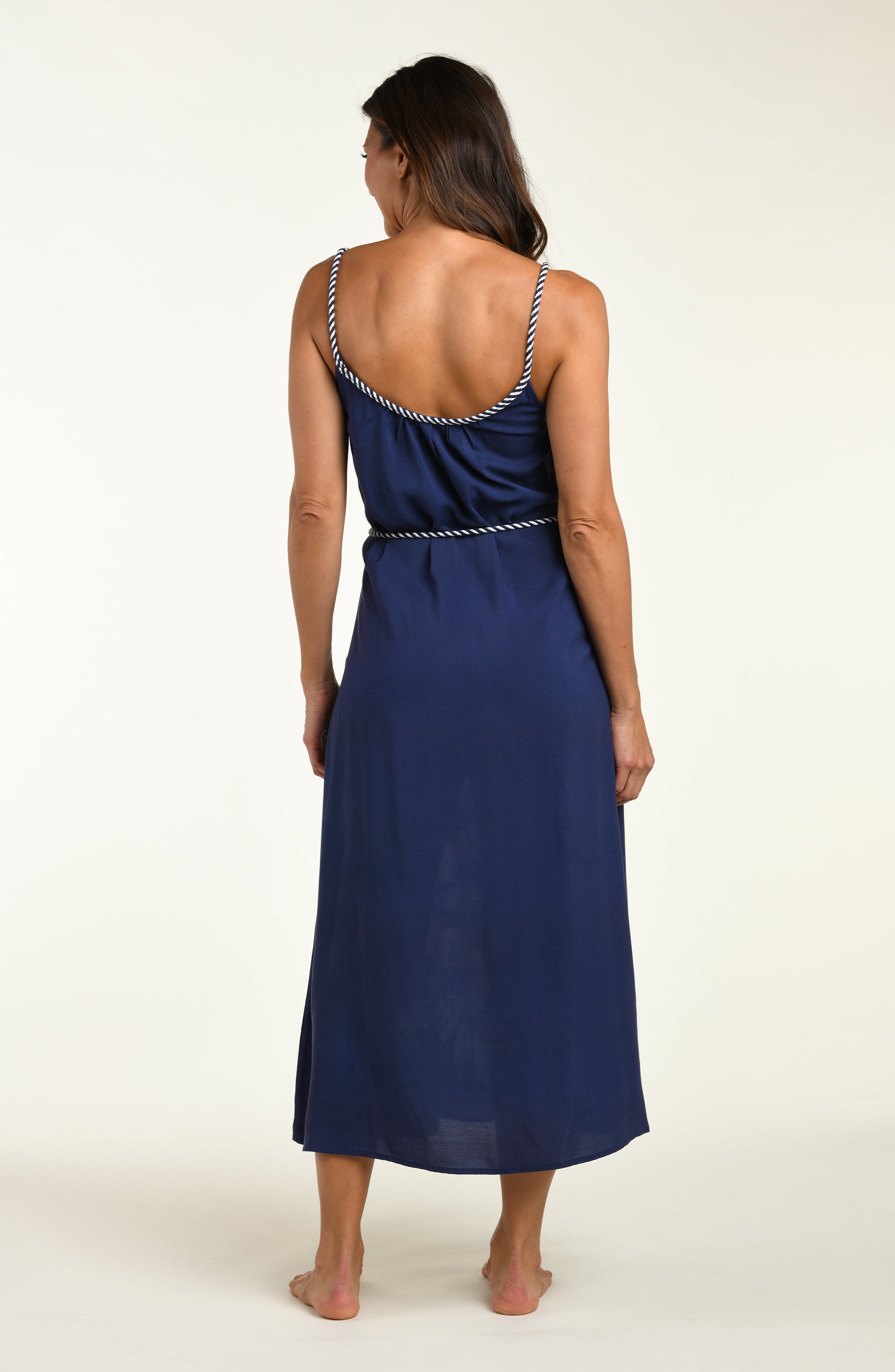 Woman wearing a navy blue cover up dress with floral patterns on a white background