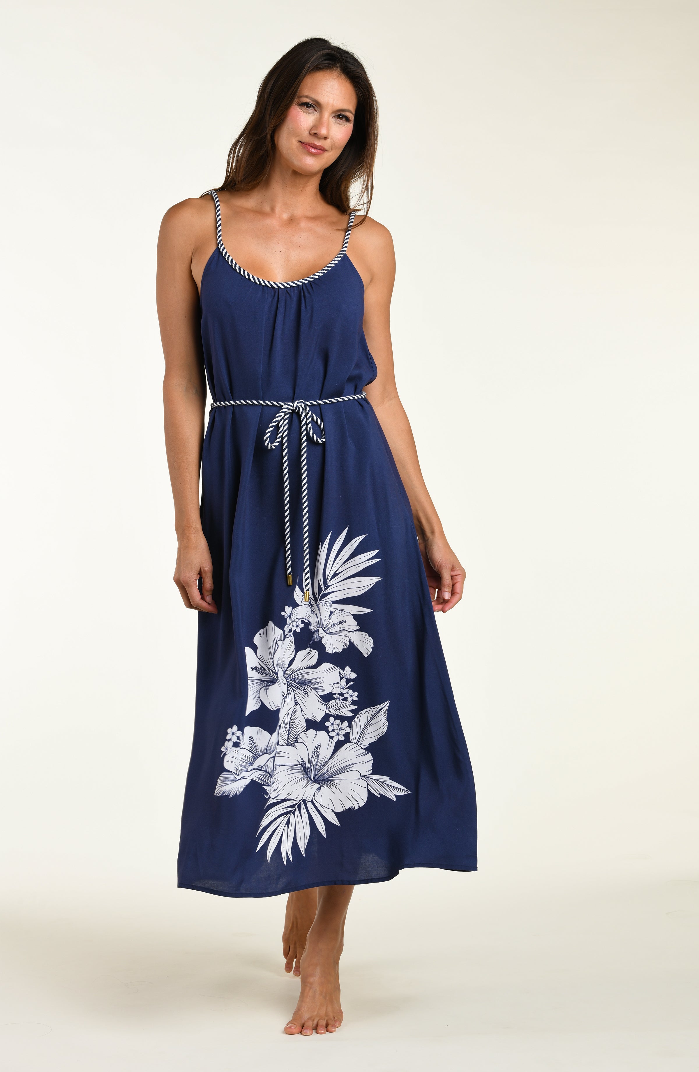 Woman wearing a navy blue cover up dress with floral patterns on a white background