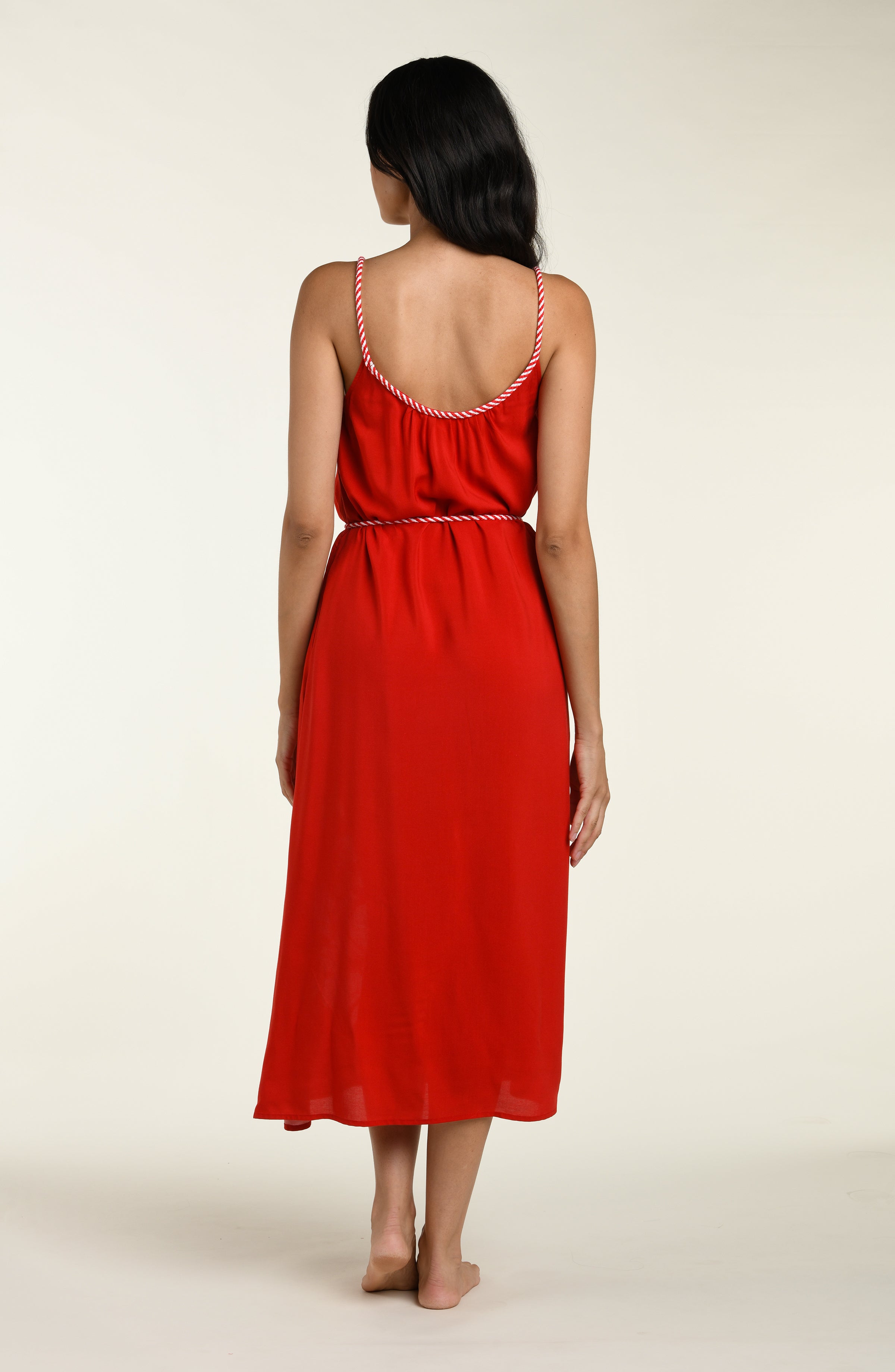 Woman wearing a red cover up dress with white floral patterns on a plain background