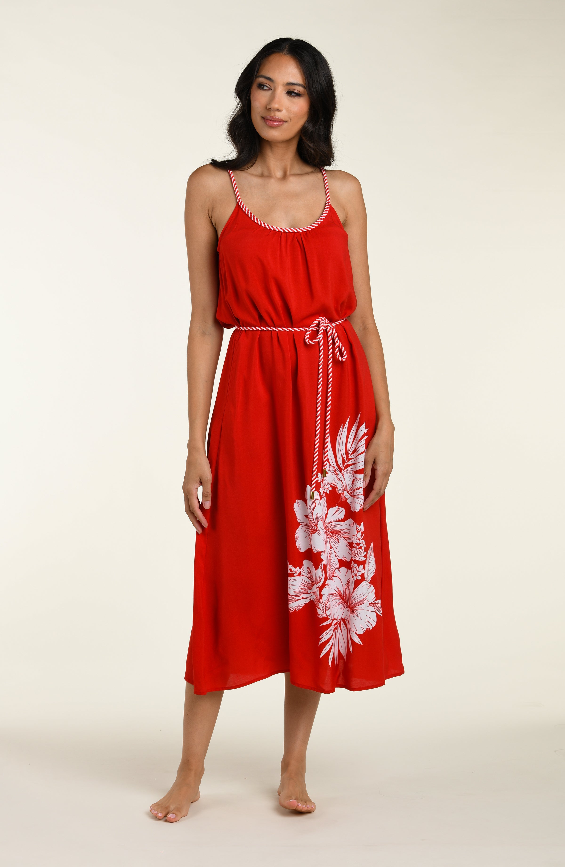 Woman wearing a red cover up dress with white floral patterns on a plain background