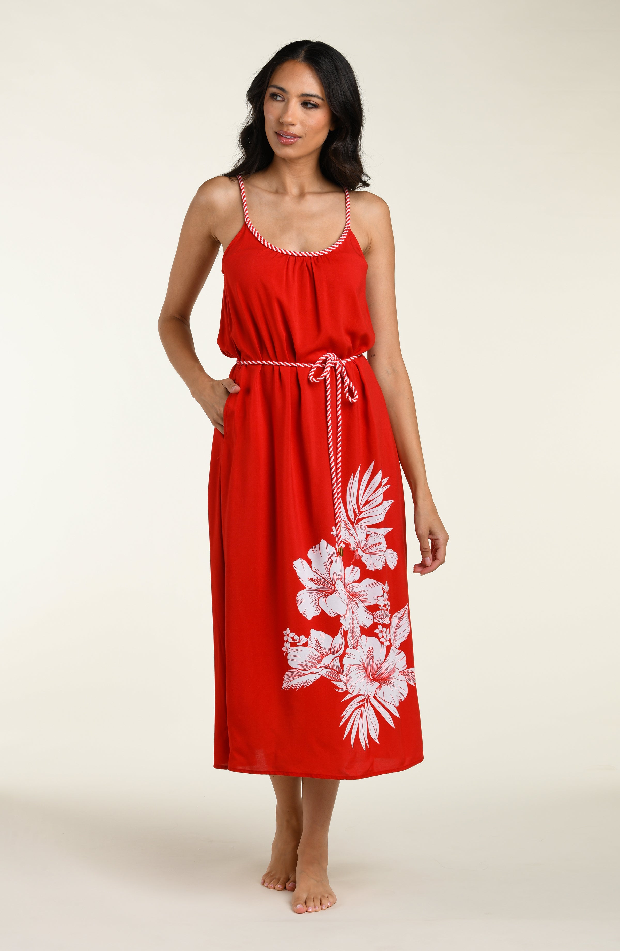 Woman wearing a red cover up dress with white floral patterns on a plain background