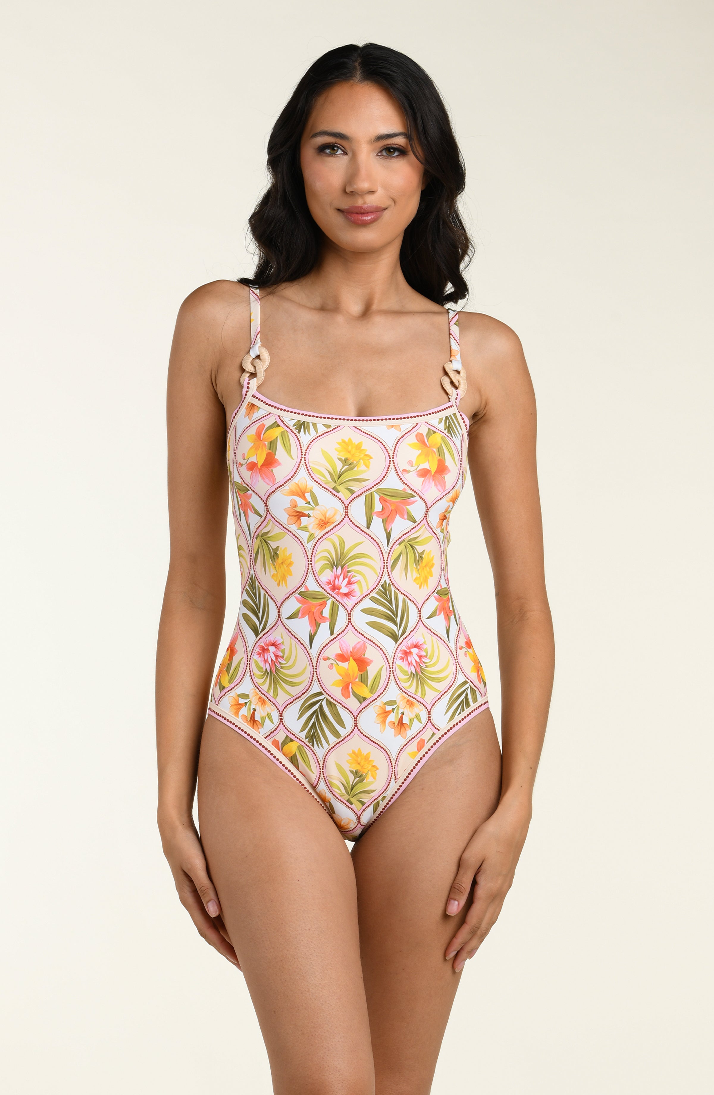 Woman wearing a floral one-piece swimsuit on a beige background