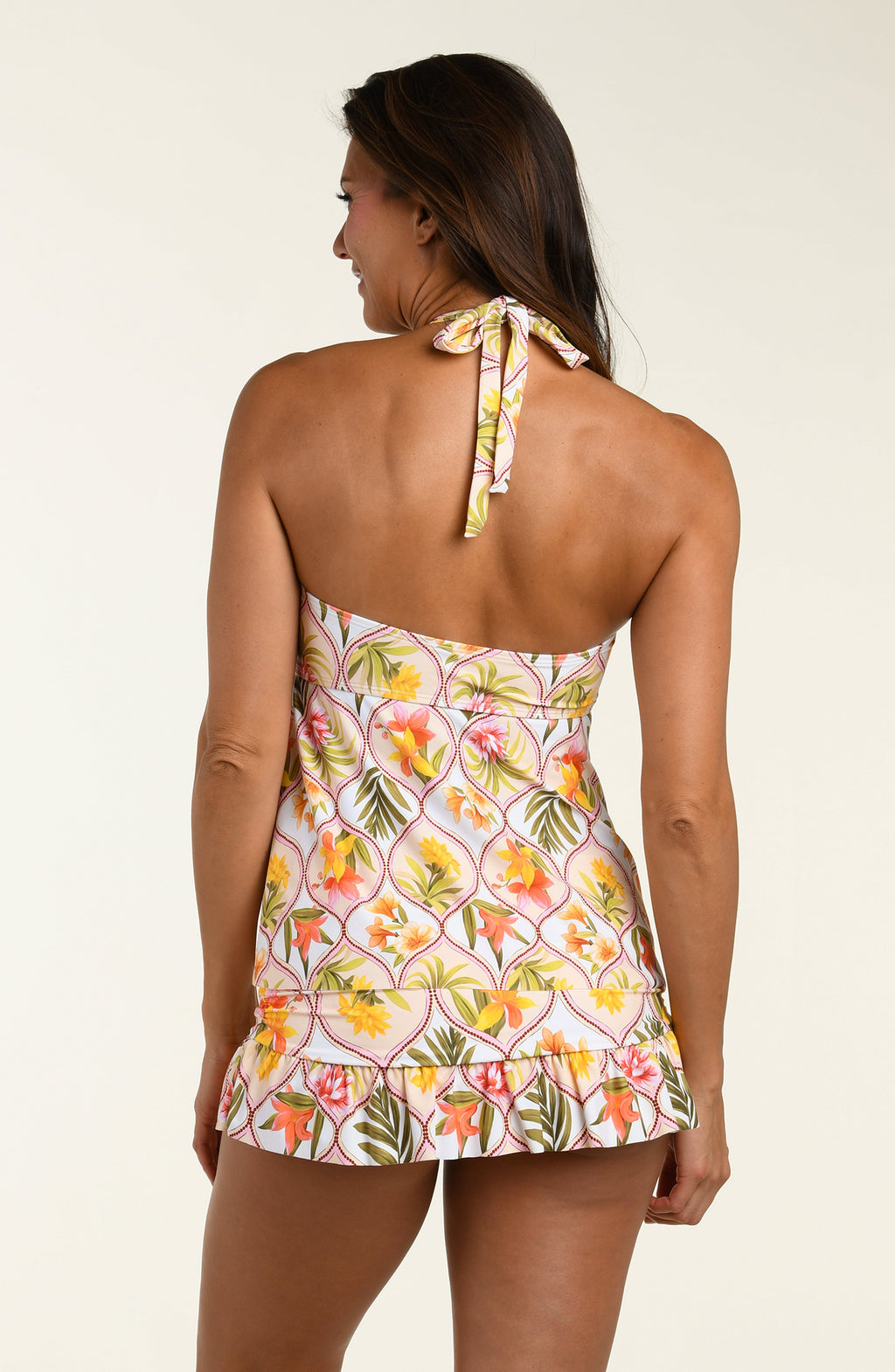 Woman wearing a floral halter tankini top and a matching swim skirt with a white background
