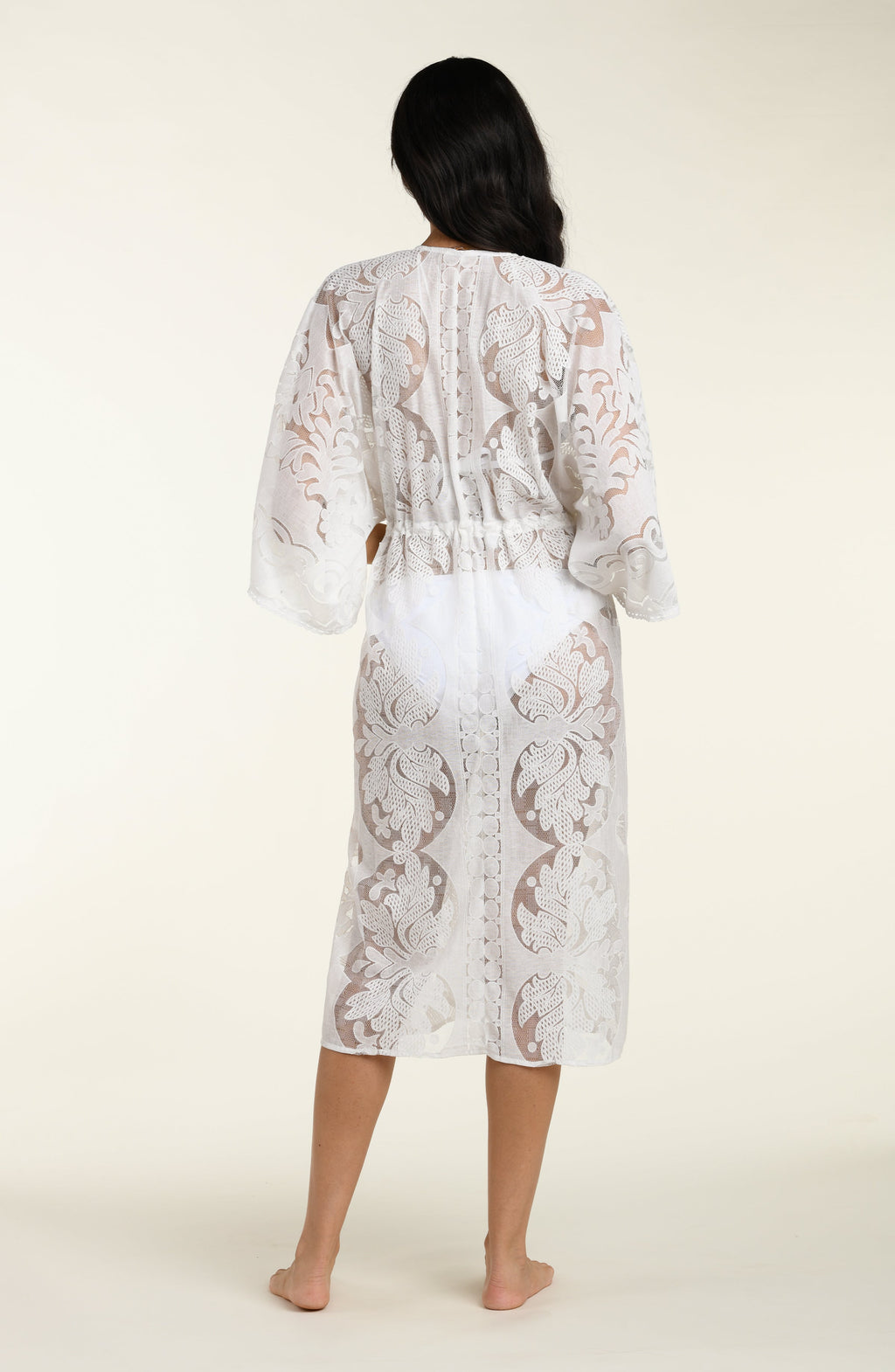 Woman wearing a white lace kimono on a plain background
