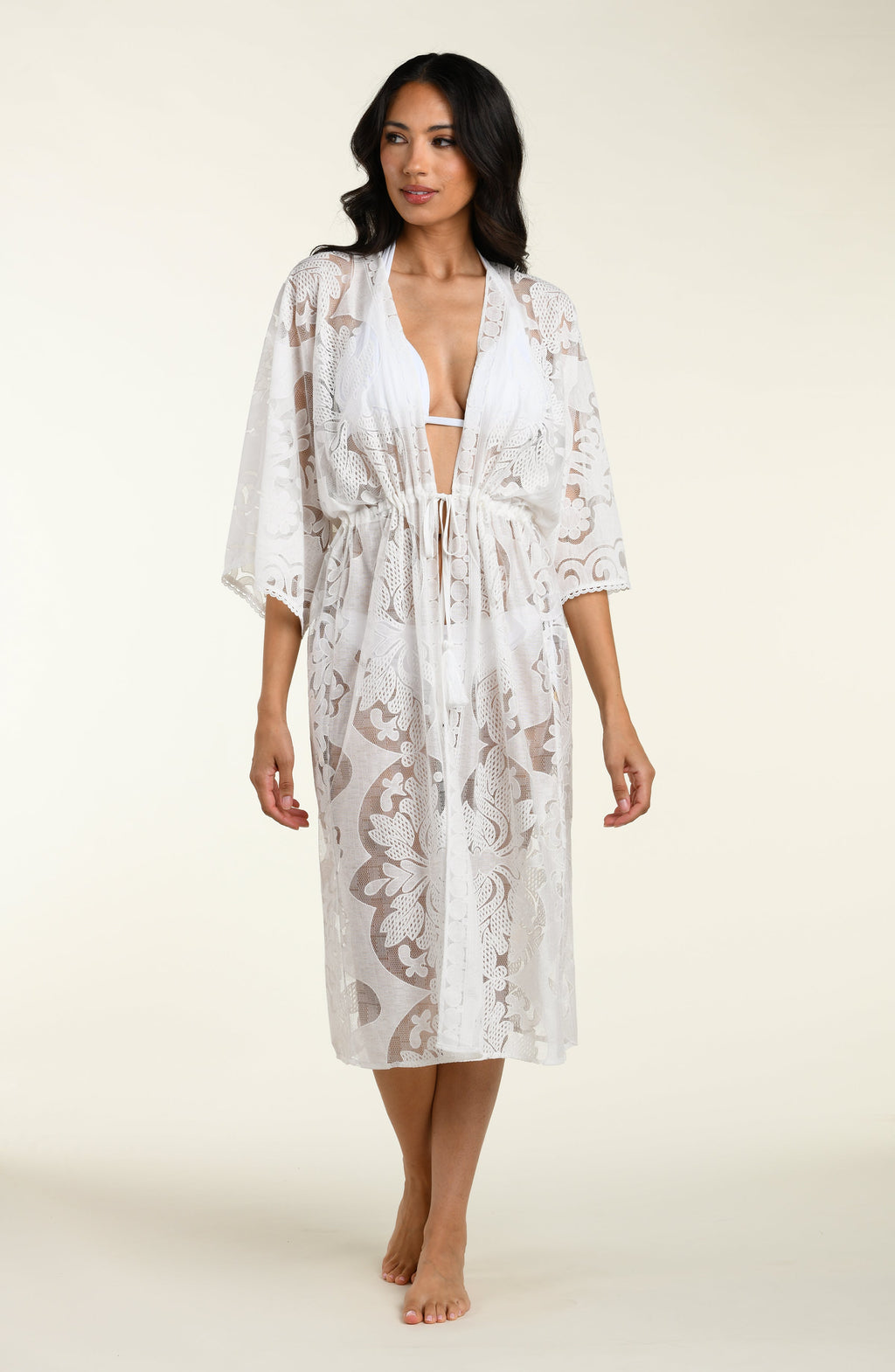 Woman wearing a white lace kimono on a plain background