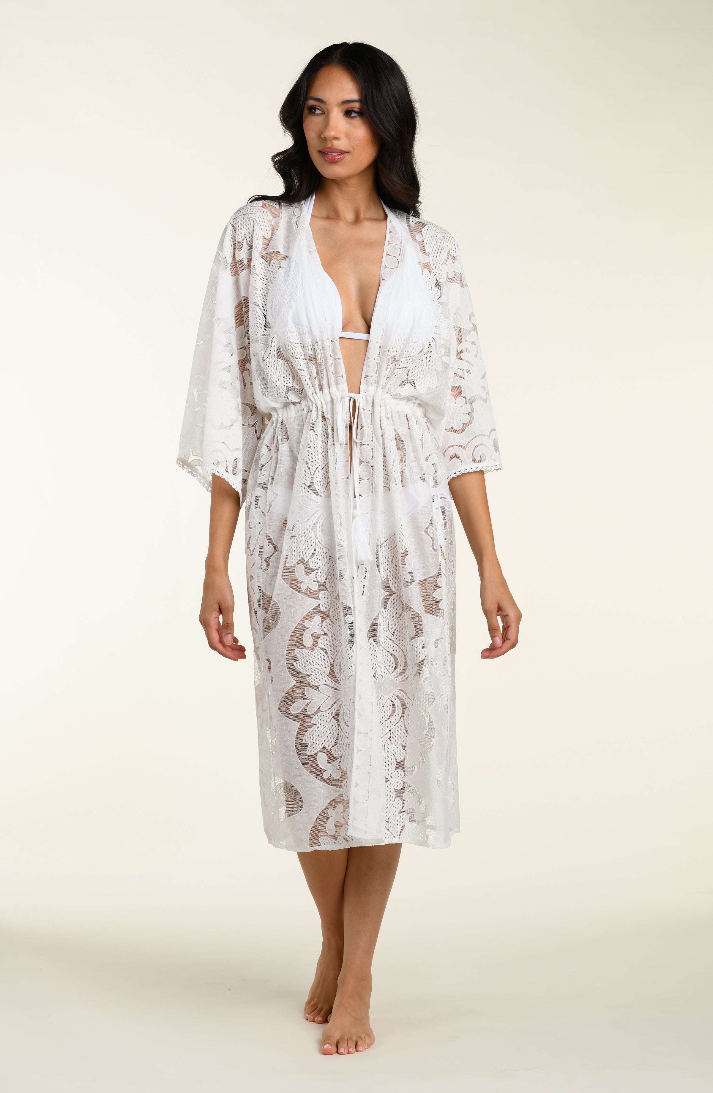 Woman wearing a white lace kimono on a plain background
