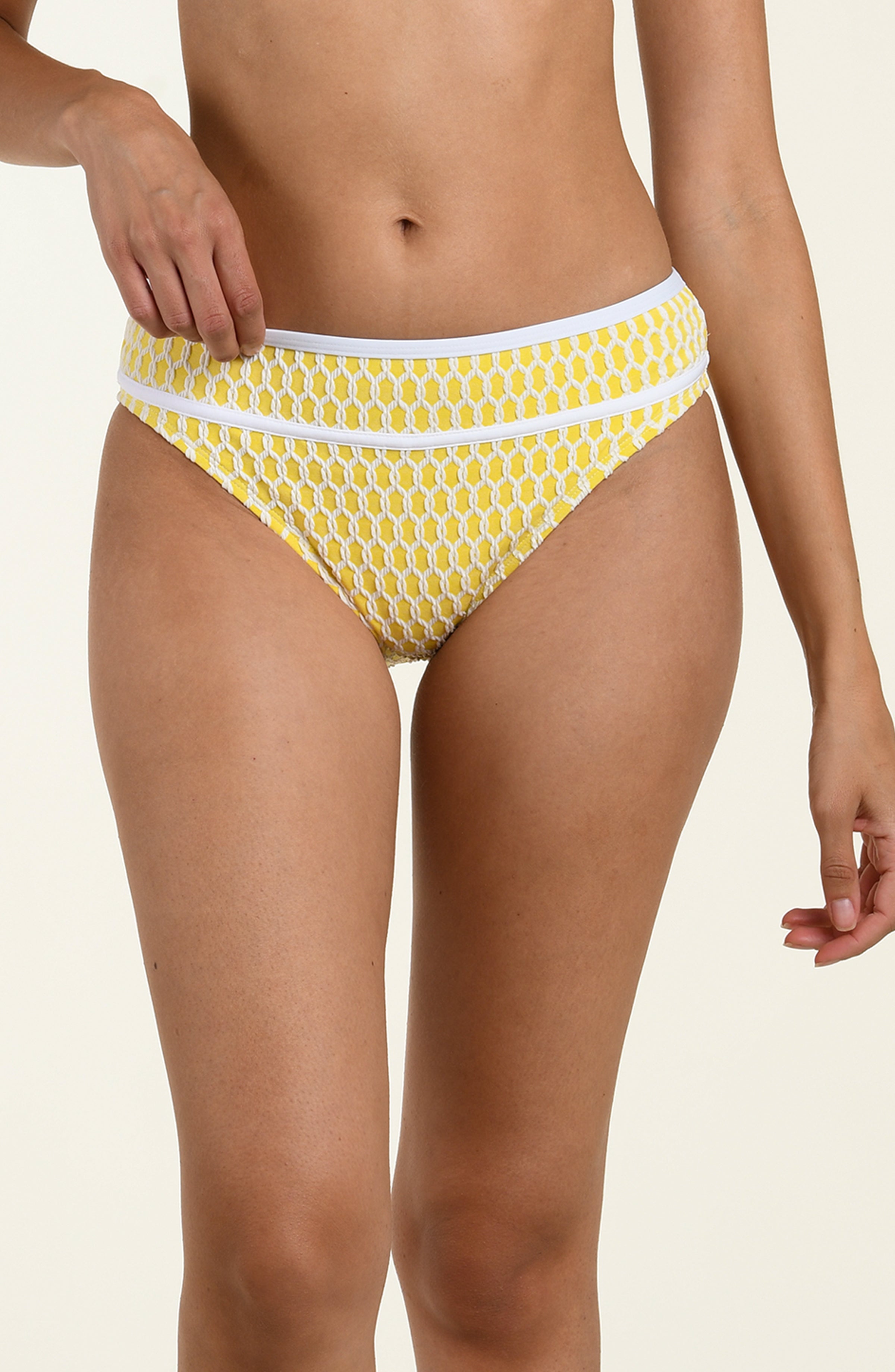 Yellow patterned bikini bottom worn by a person on a beige background