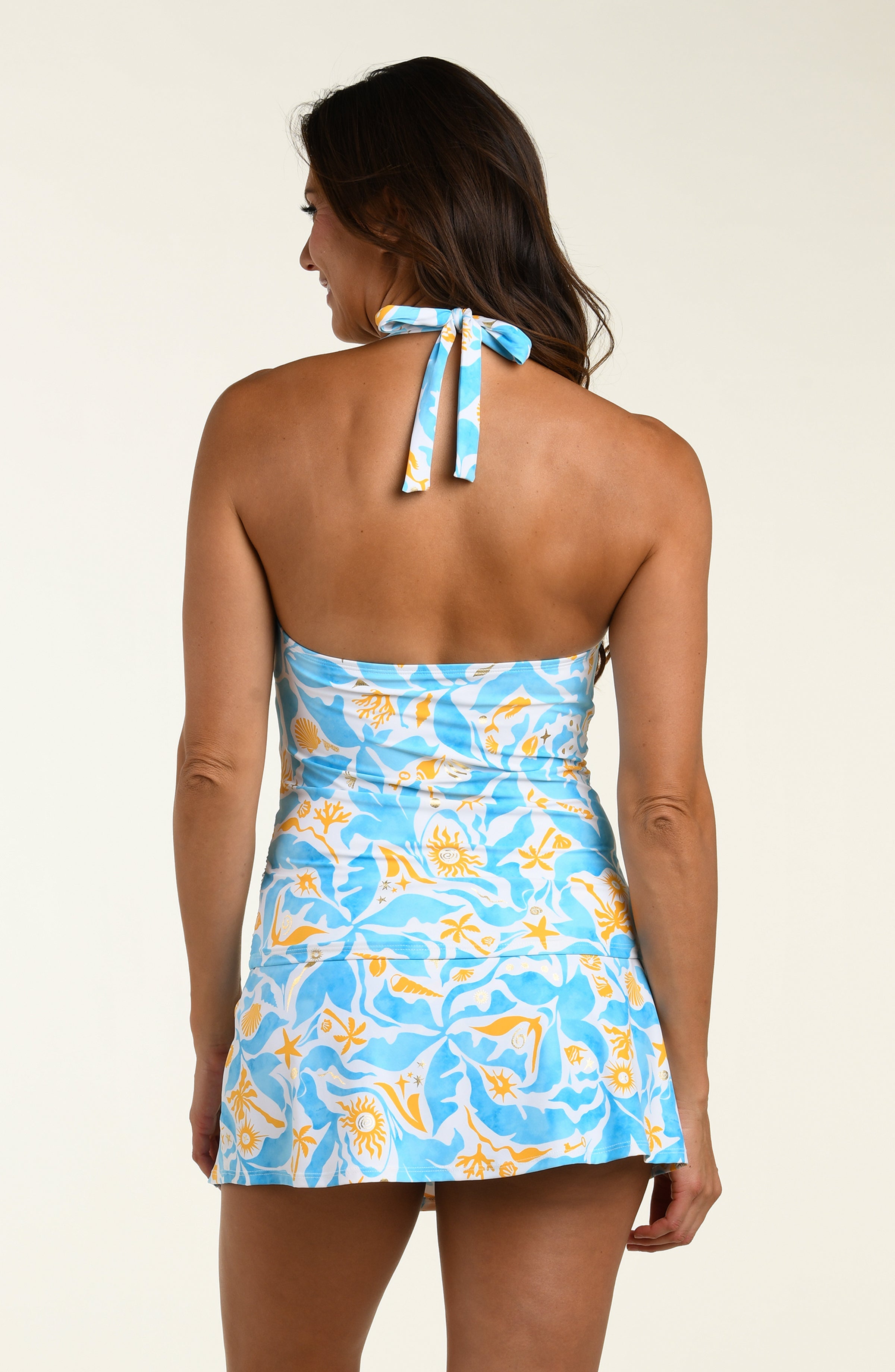 Woman wearing a blue and yellow patterned tankini top and matching swim skirt against a white background.