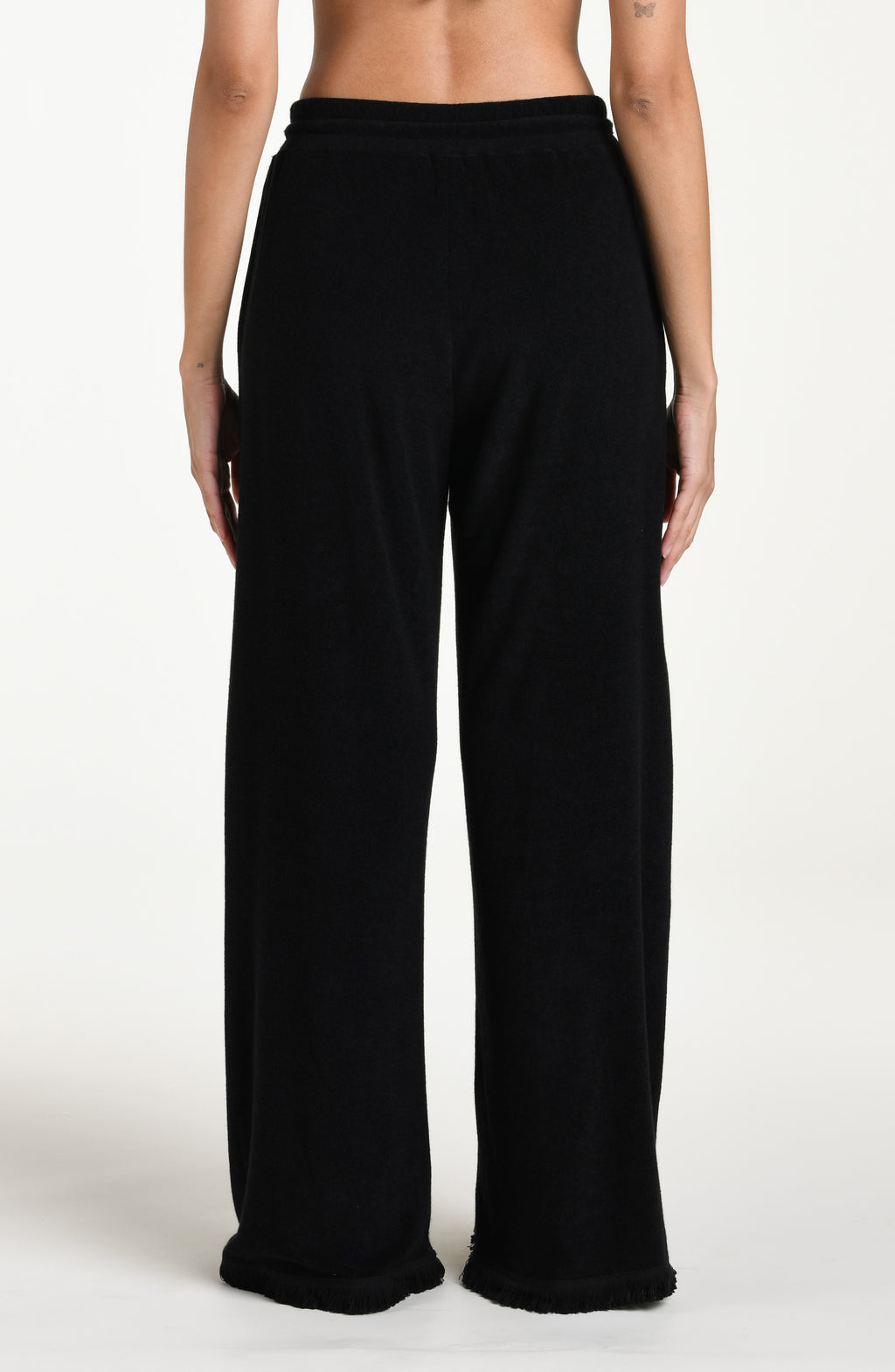 Black cover up beach pants worn by a person on a beige background