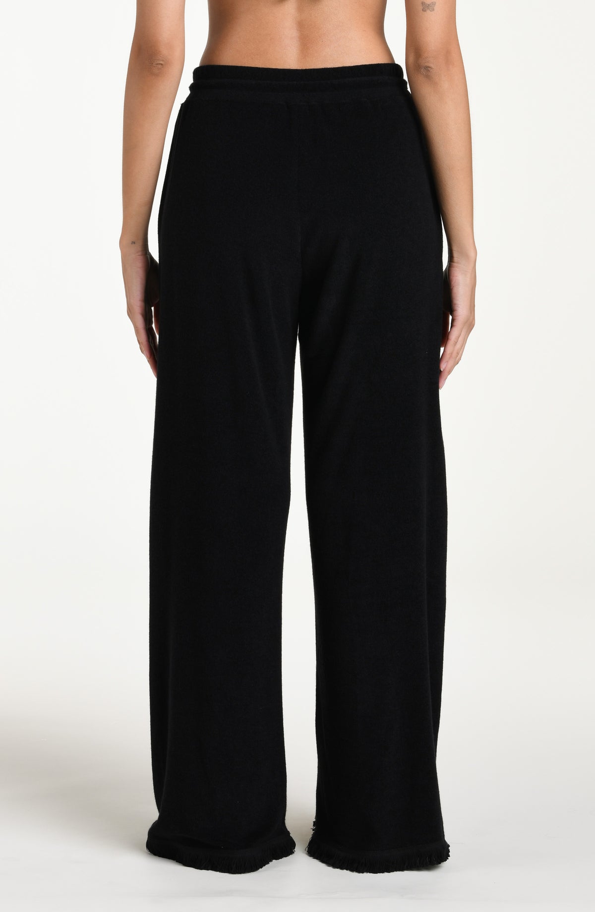 Black cover up beach pants worn by a person on a beige background