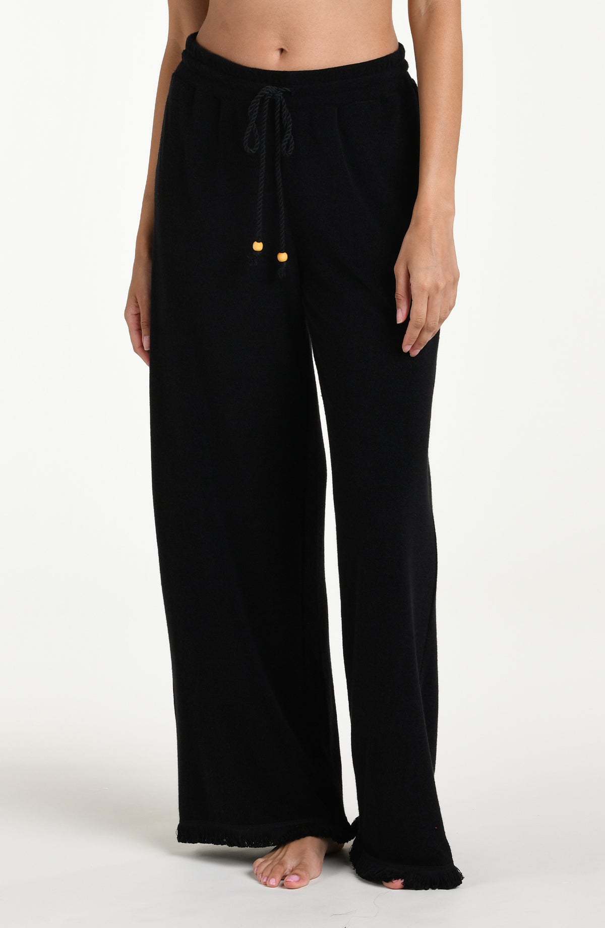Black cover up beach pants worn by a person on a beige background