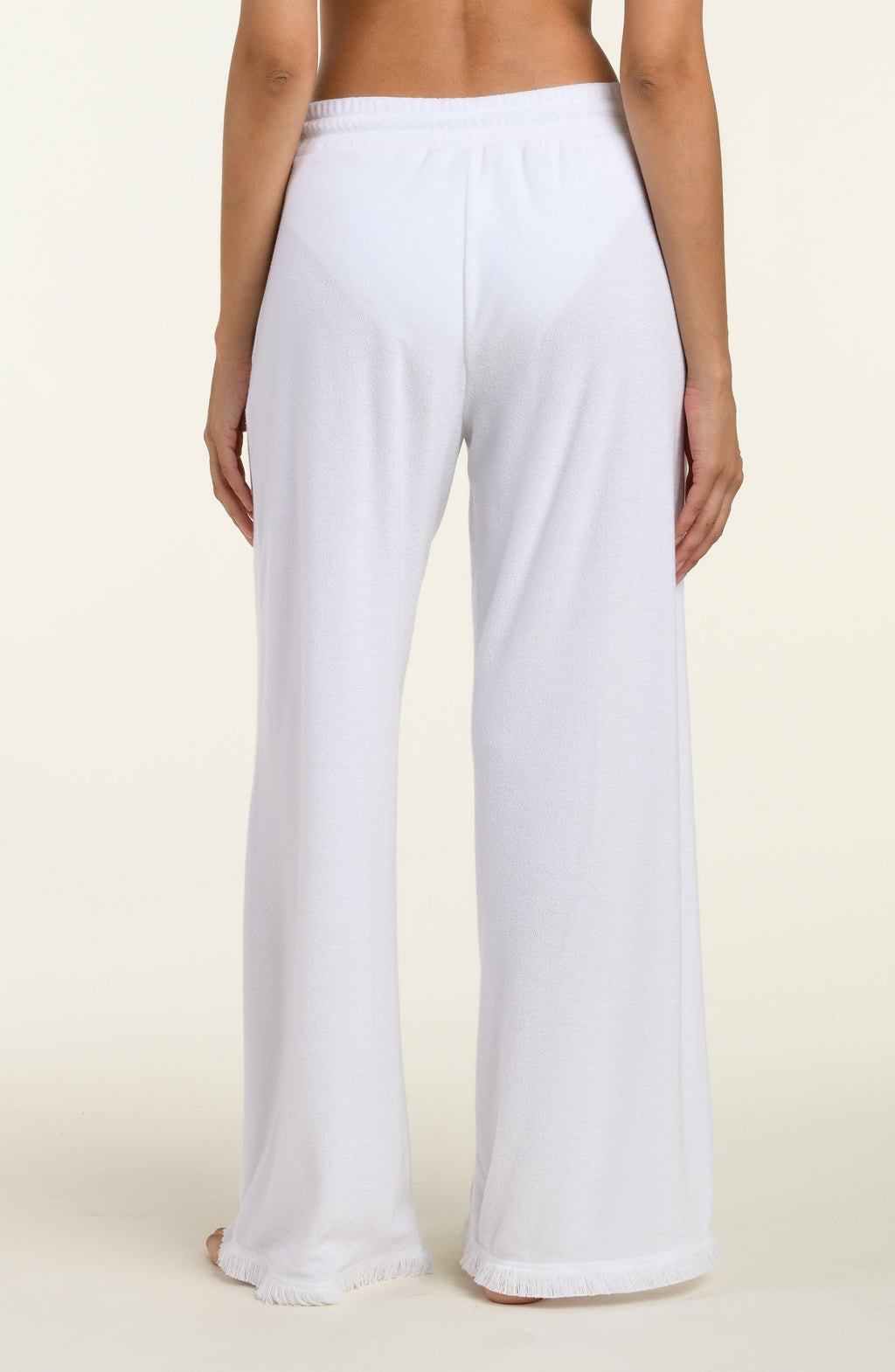 White cover up beach pants worn by a person on a beige background