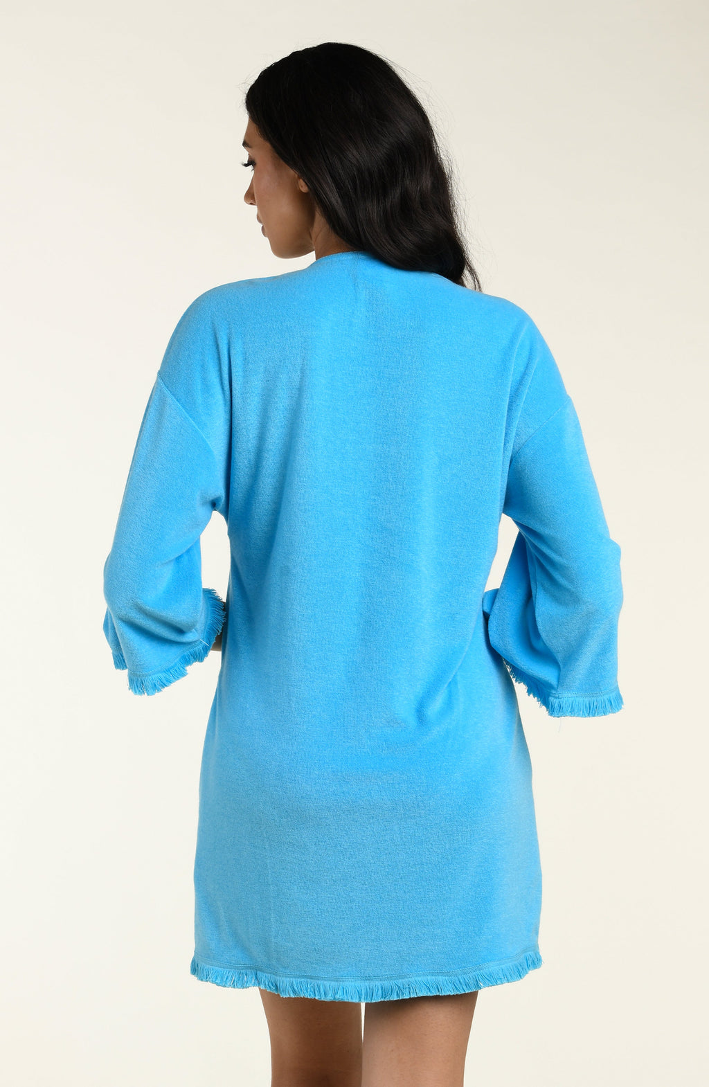 Woman wearing a blue cover-up tunic on a beige background