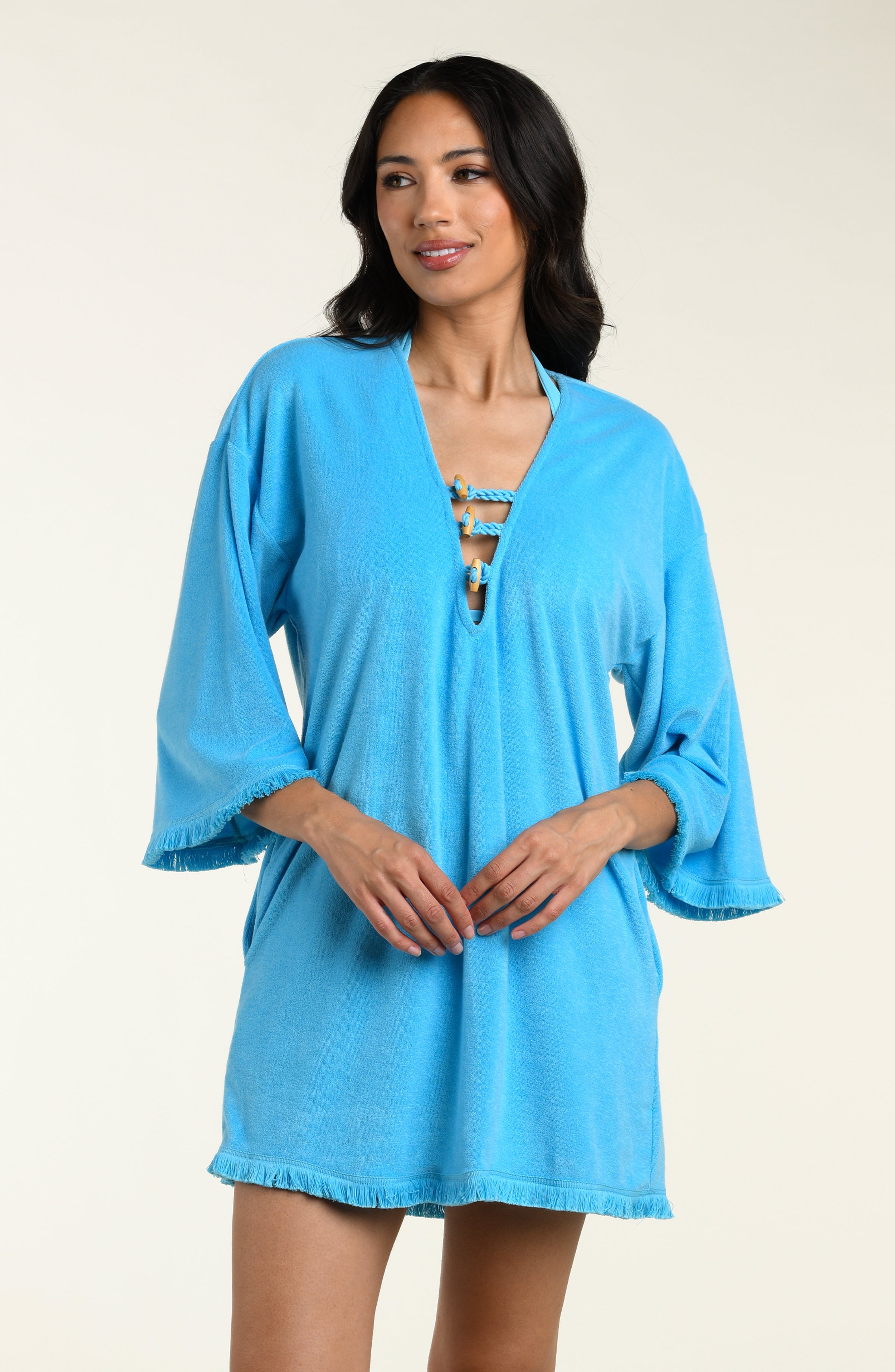 Woman wearing a blue cover-up tunic on a beige background