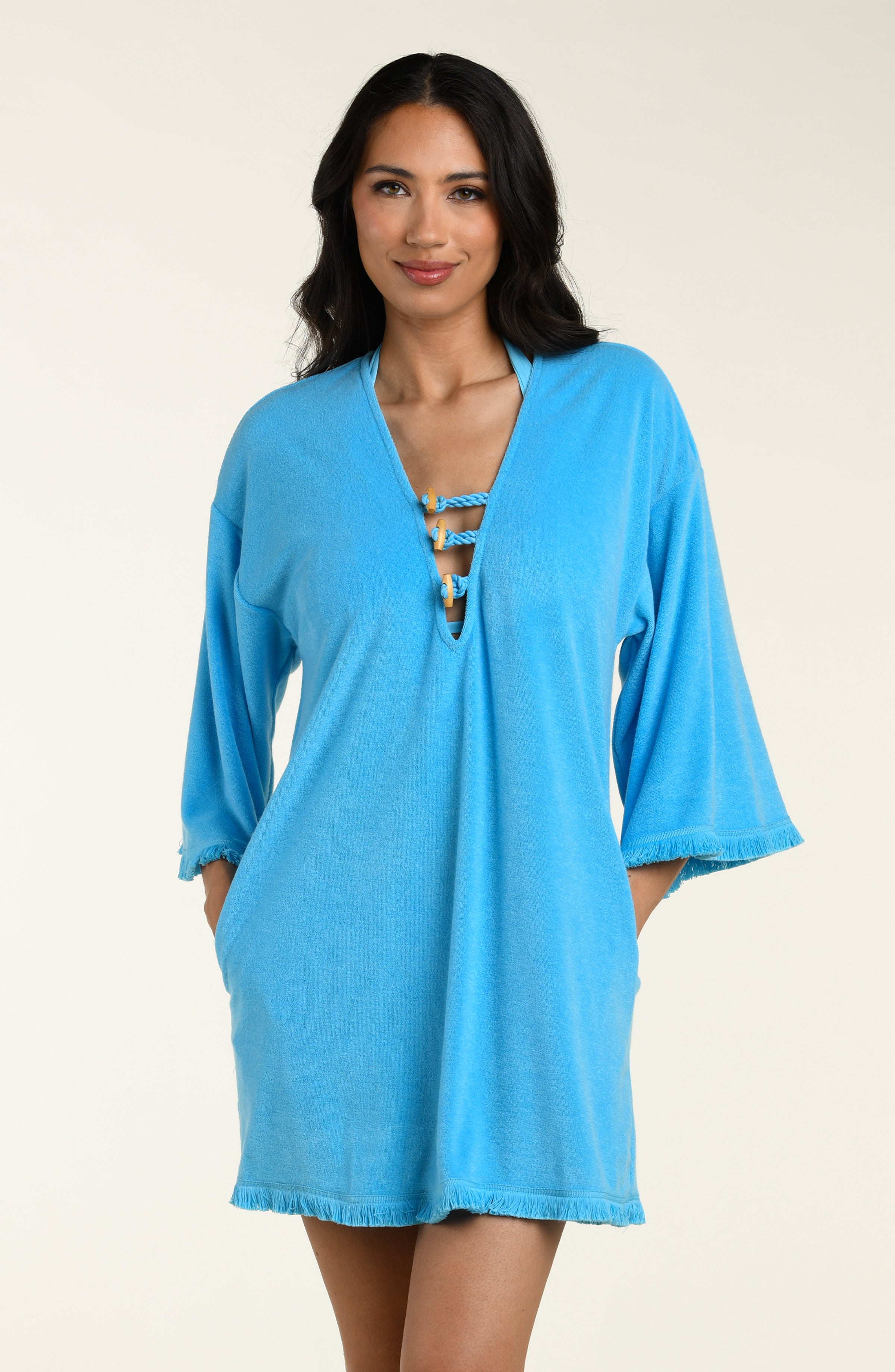 Woman wearing a blue cover-up tunic on a beige background