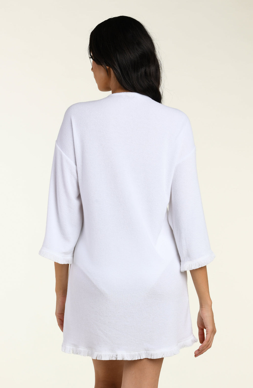 Woman wearing a white cover-up tunic  with lace-up front on a beige background