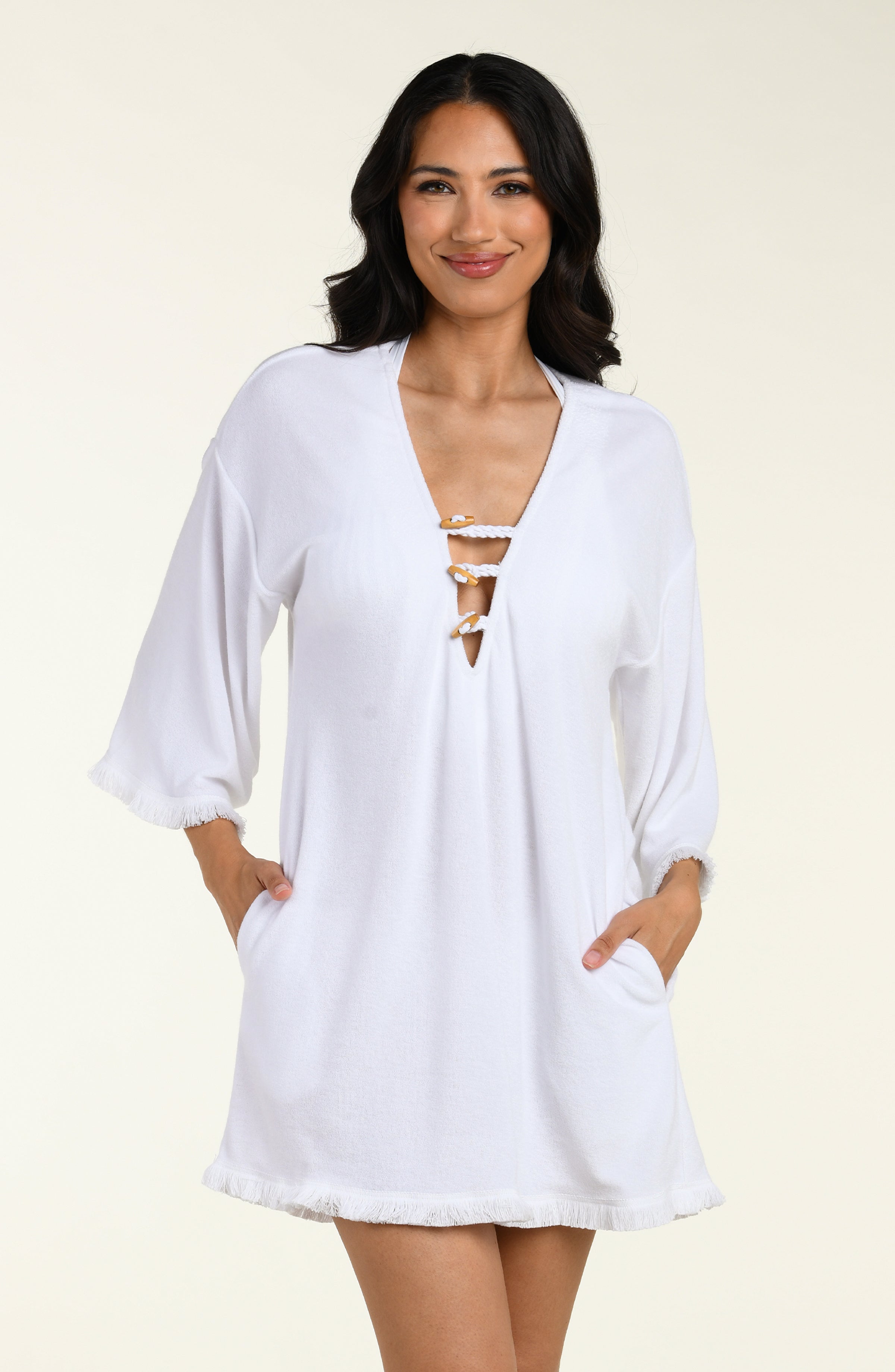 Woman wearing a white cover-up tunic  with lace-up front on a beige background