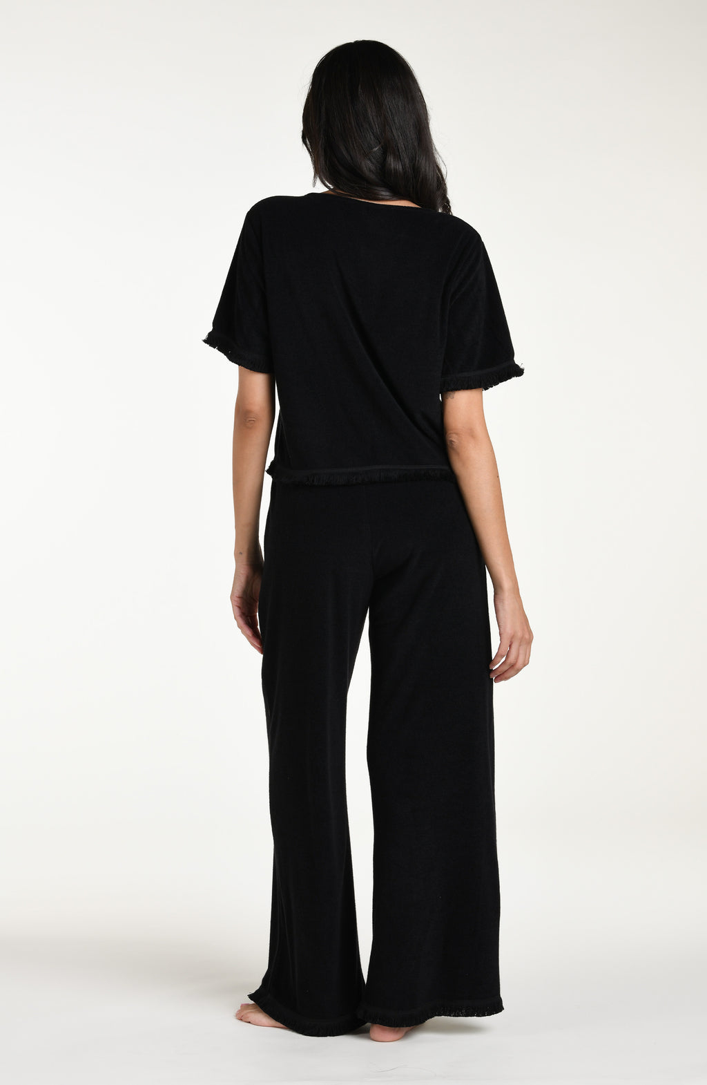Woman wearing a black short sleeve top and matching pants against a white background