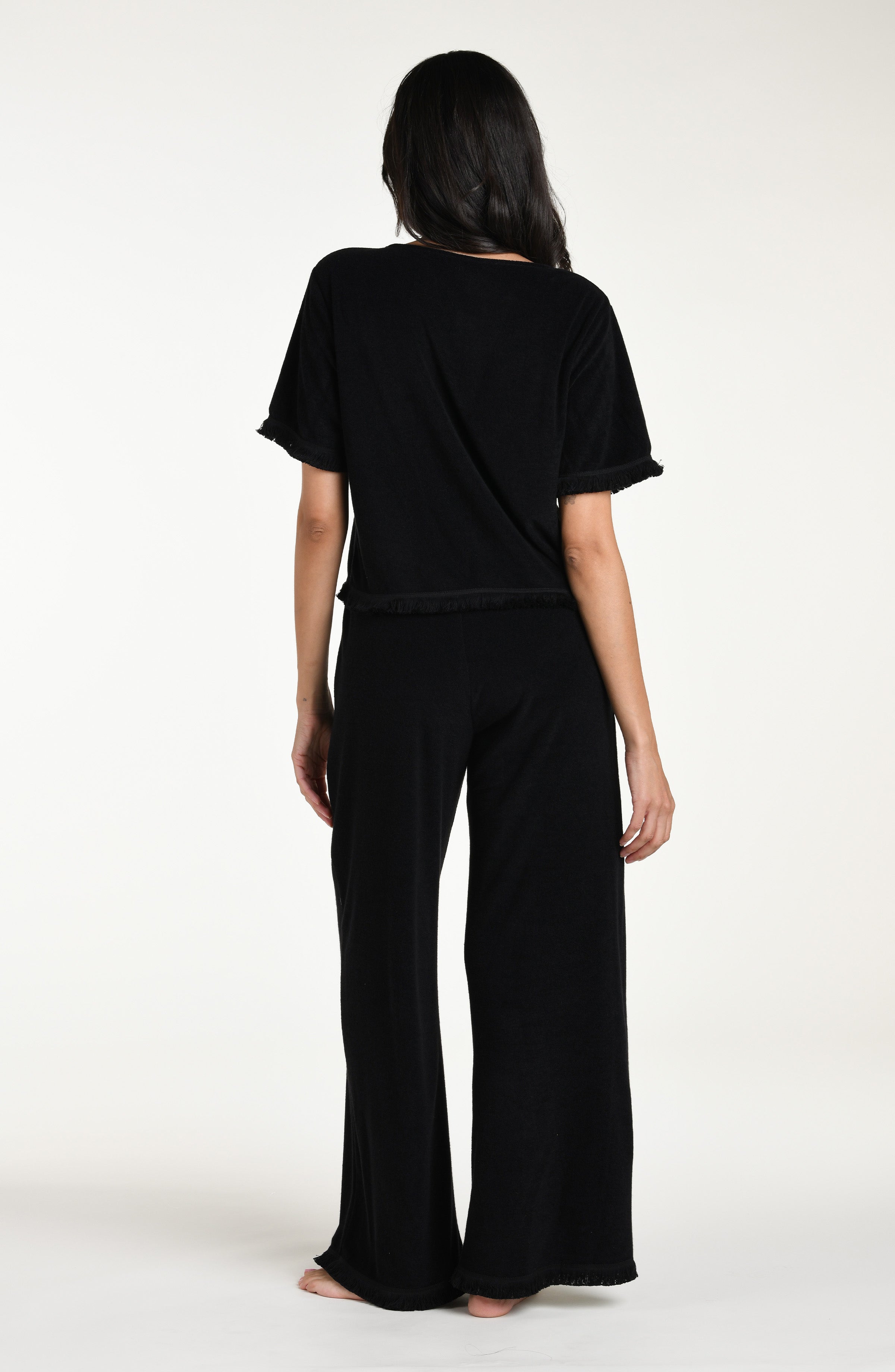 Woman wearing a black short sleeve top and matching pants against a white background