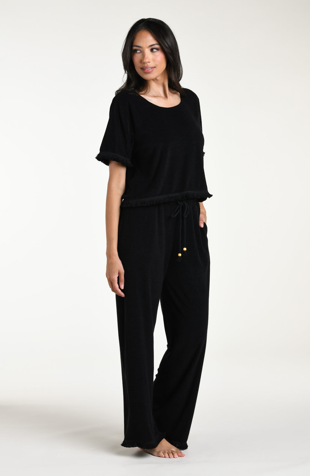 Woman wearing a black short sleeve top and matching pants against a white background