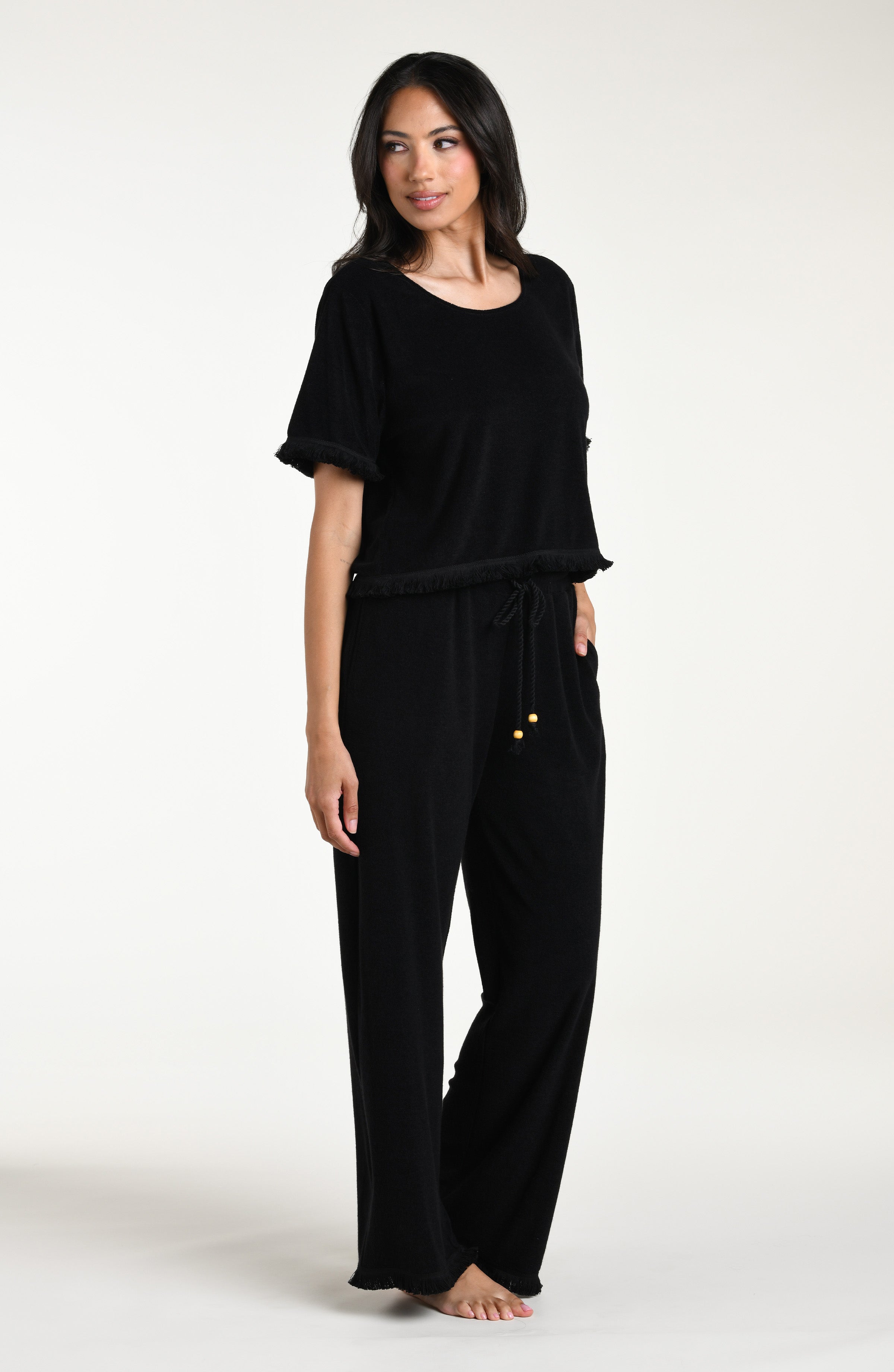 Woman wearing a black short sleeve top and matching pants against a white background
