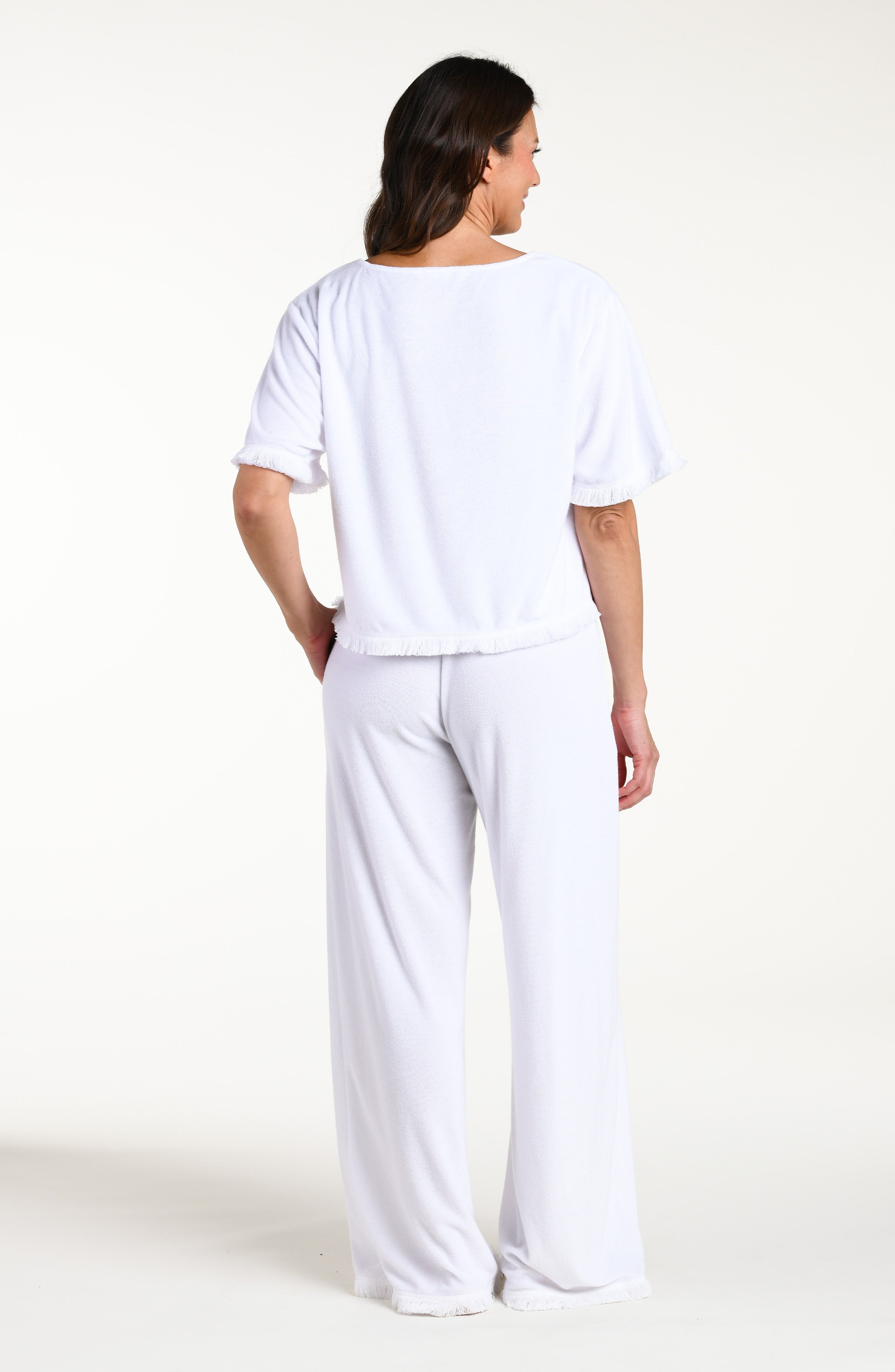 Woman wearing a white short sleeve top and matching pants against a white background