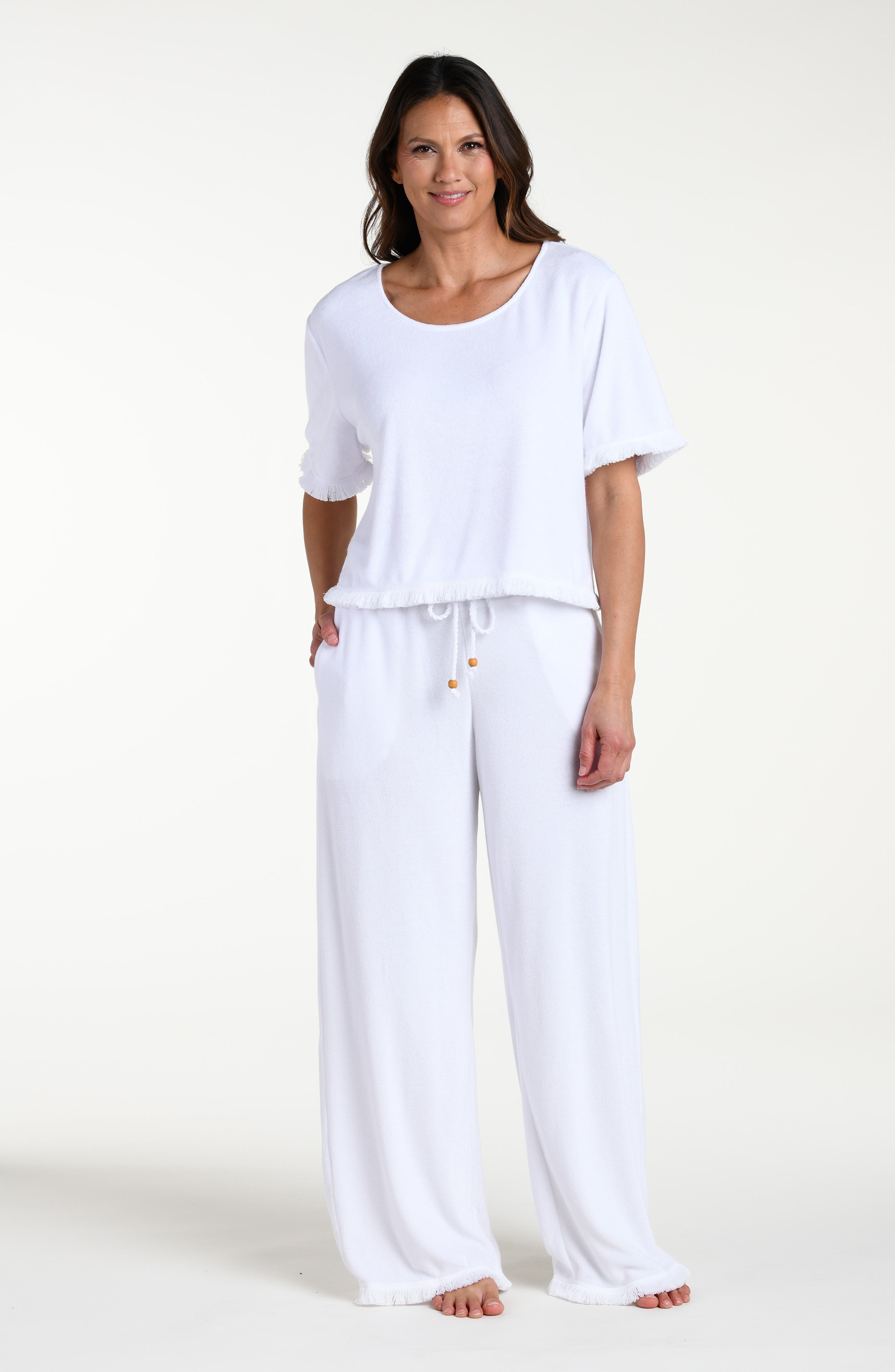 Woman wearing a white short sleeve top and matching pants against a white background
