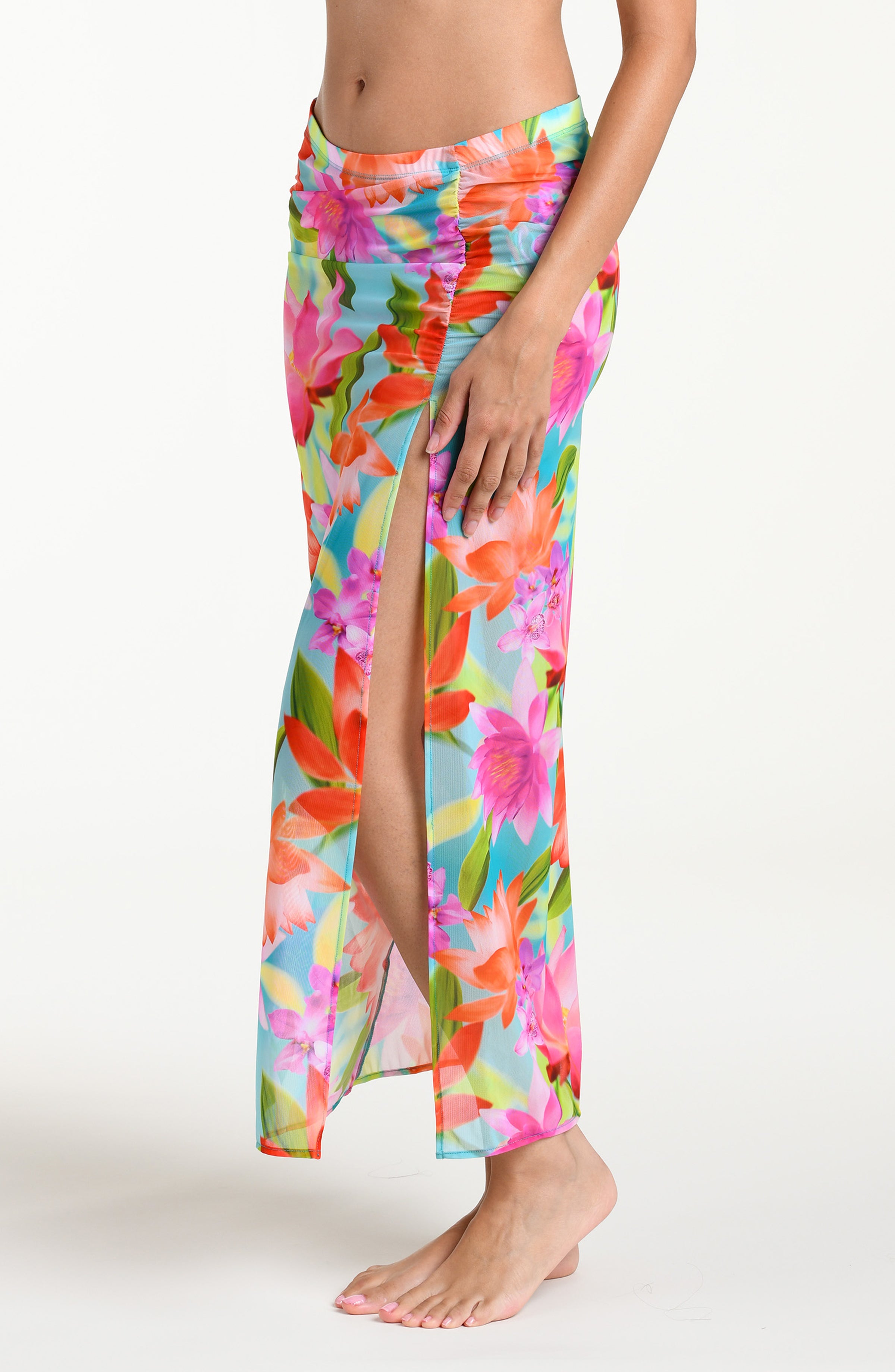 Woman wearing a bright floral midi skirt cover up against a white background