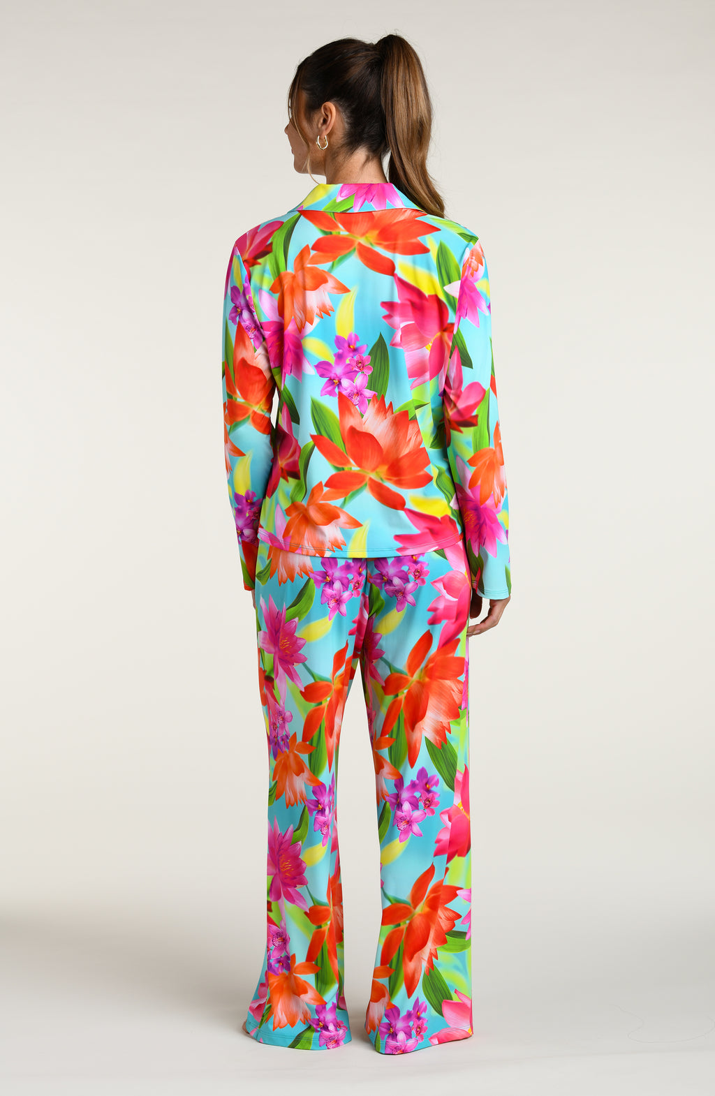 Woman wearing a colorful floral pajama pant set against a white background