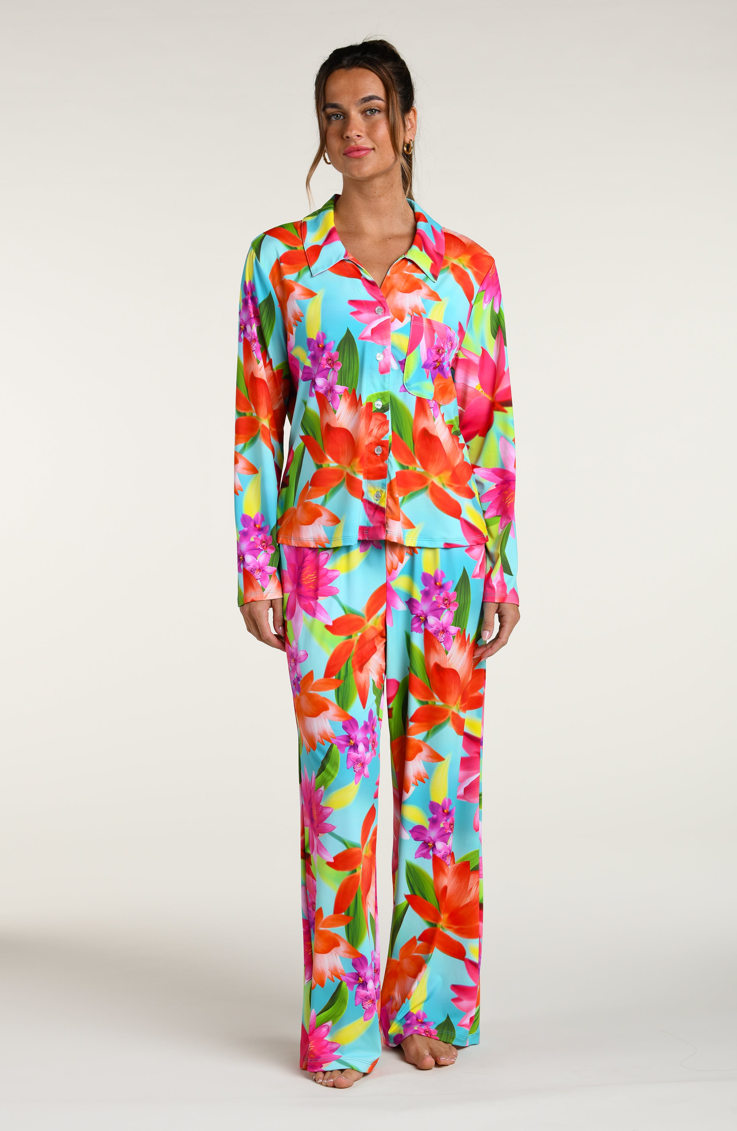 Woman wearing a colorful floral pajama pant set against a white background
