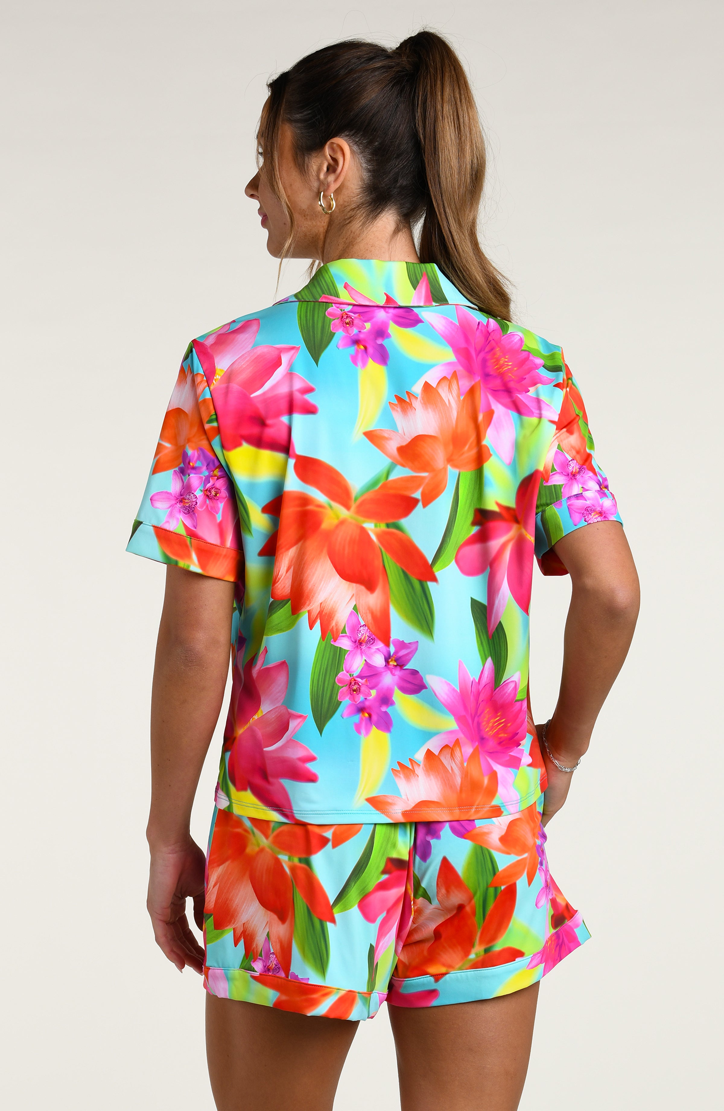 Woman wearing a colorful floral pajama set against a white background