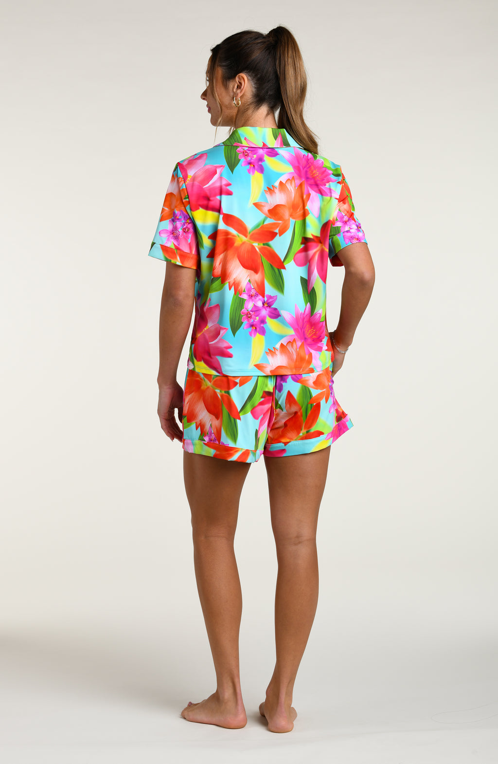 Woman wearing a colorful floral pajama set against a white background