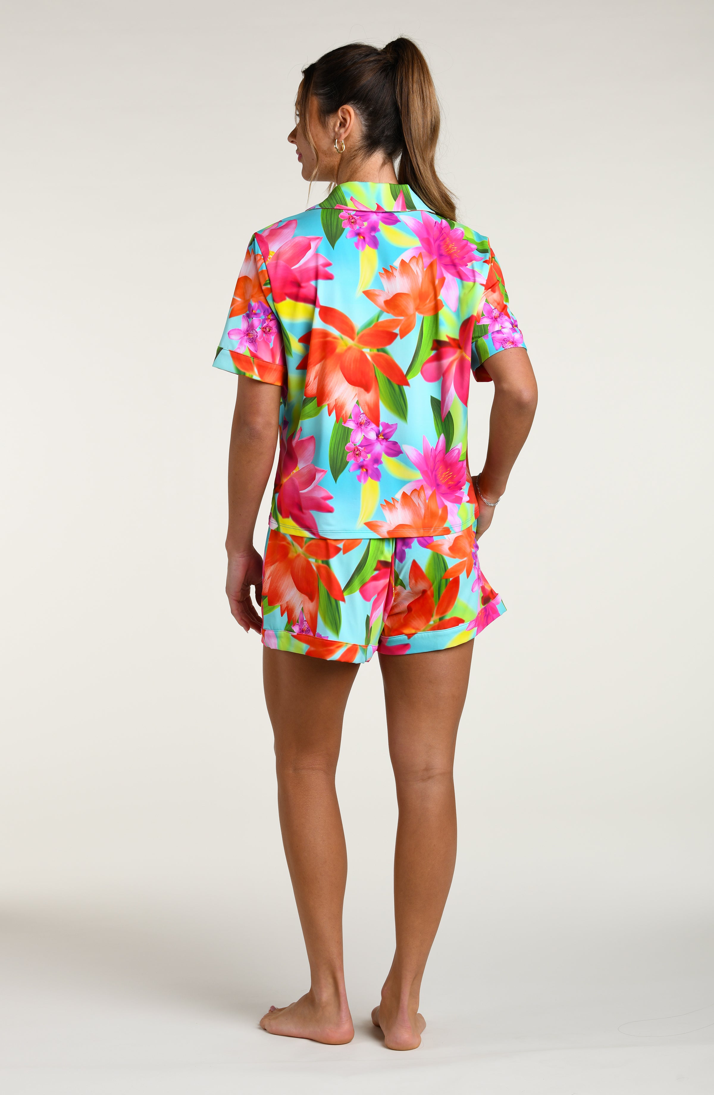 Woman wearing a colorful floral pajama set against a white background