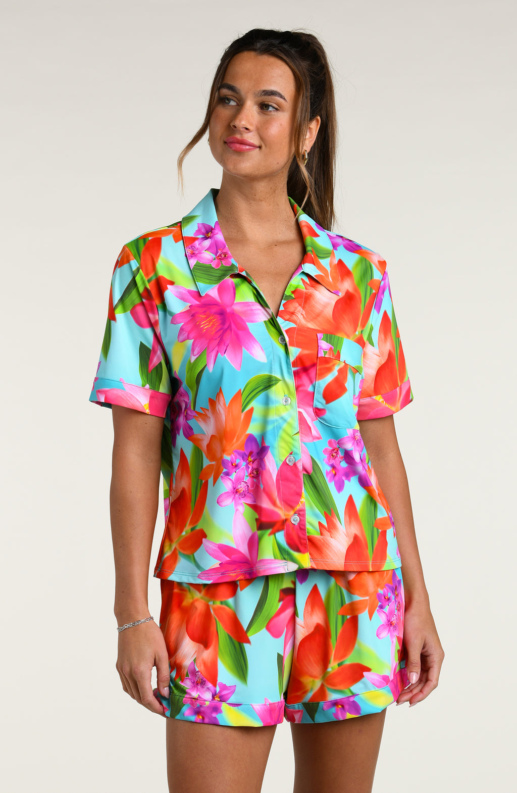 Woman wearing a colorful floral pajama set against a white background